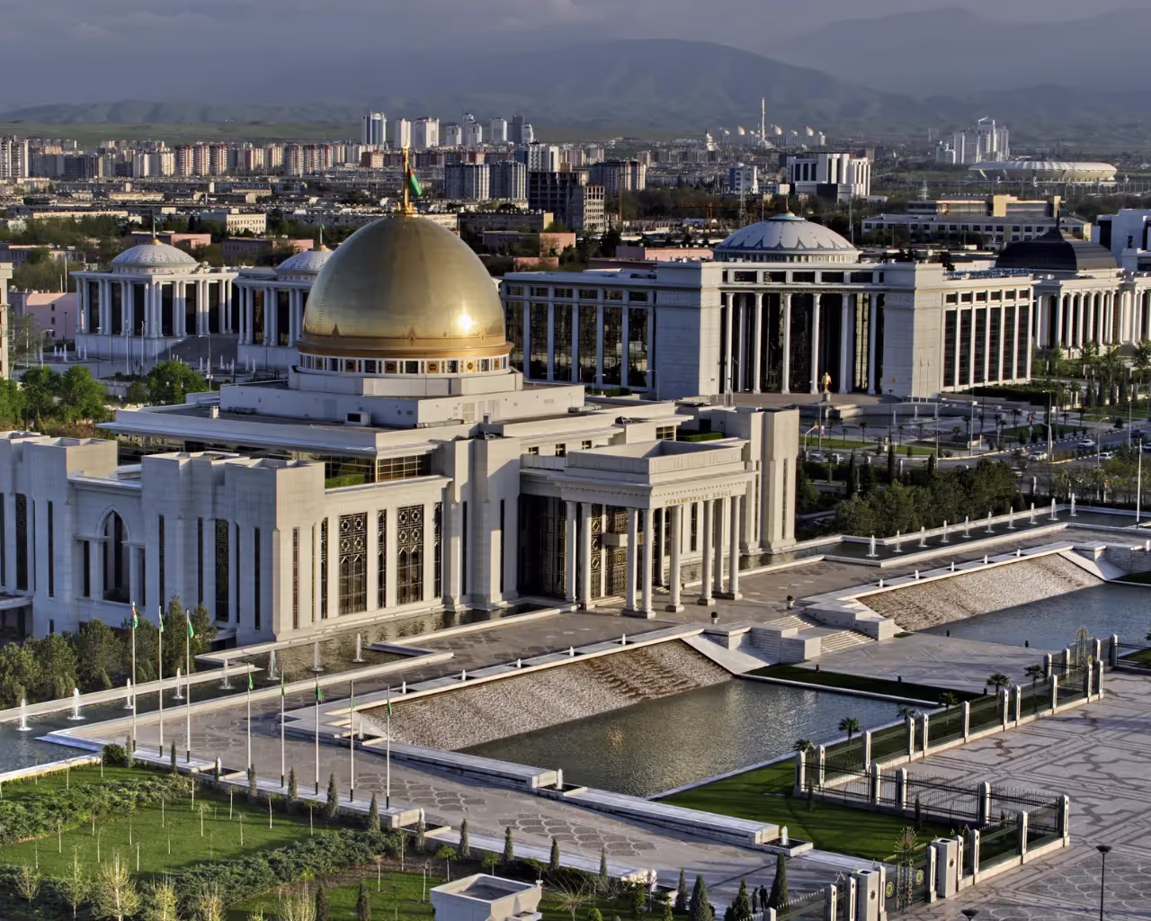The grand Presidential Palace in Ashgabat, Turkmenistan, with a golden dome and lush gardens.