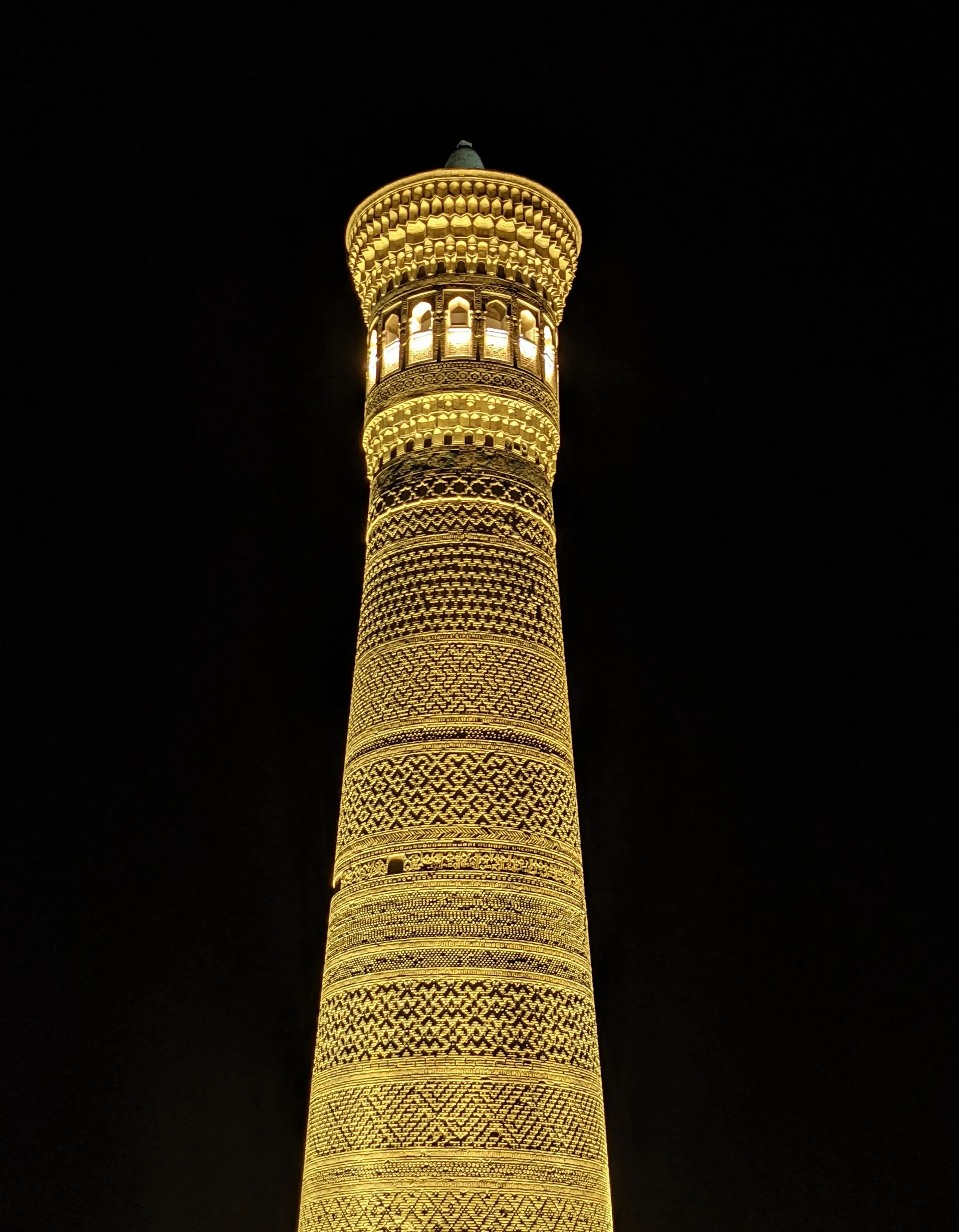 A glowing nighttime view of the historic Kalyan Minaret, an iconic symbol of Bukhara’s Silk Road past.
