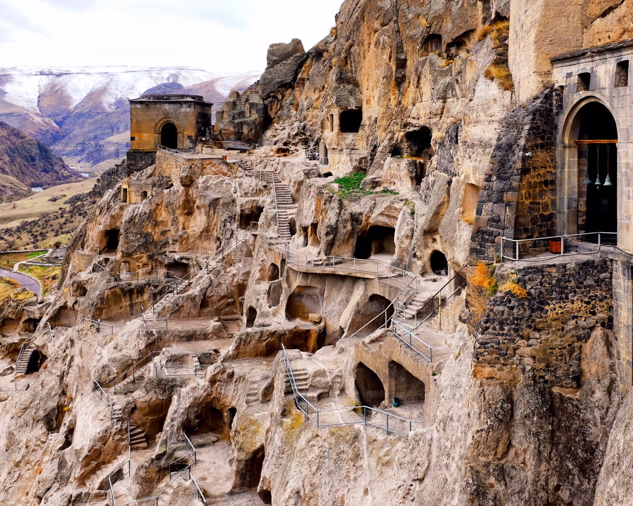 The ancient cave city of Vardzia, Georgia, with carved dwellings and stairways on a rocky cliffside.