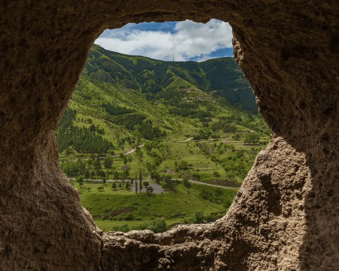 View of Vardzia cave monastery in Georgia, an ancient rock-hewn site in a green valley.