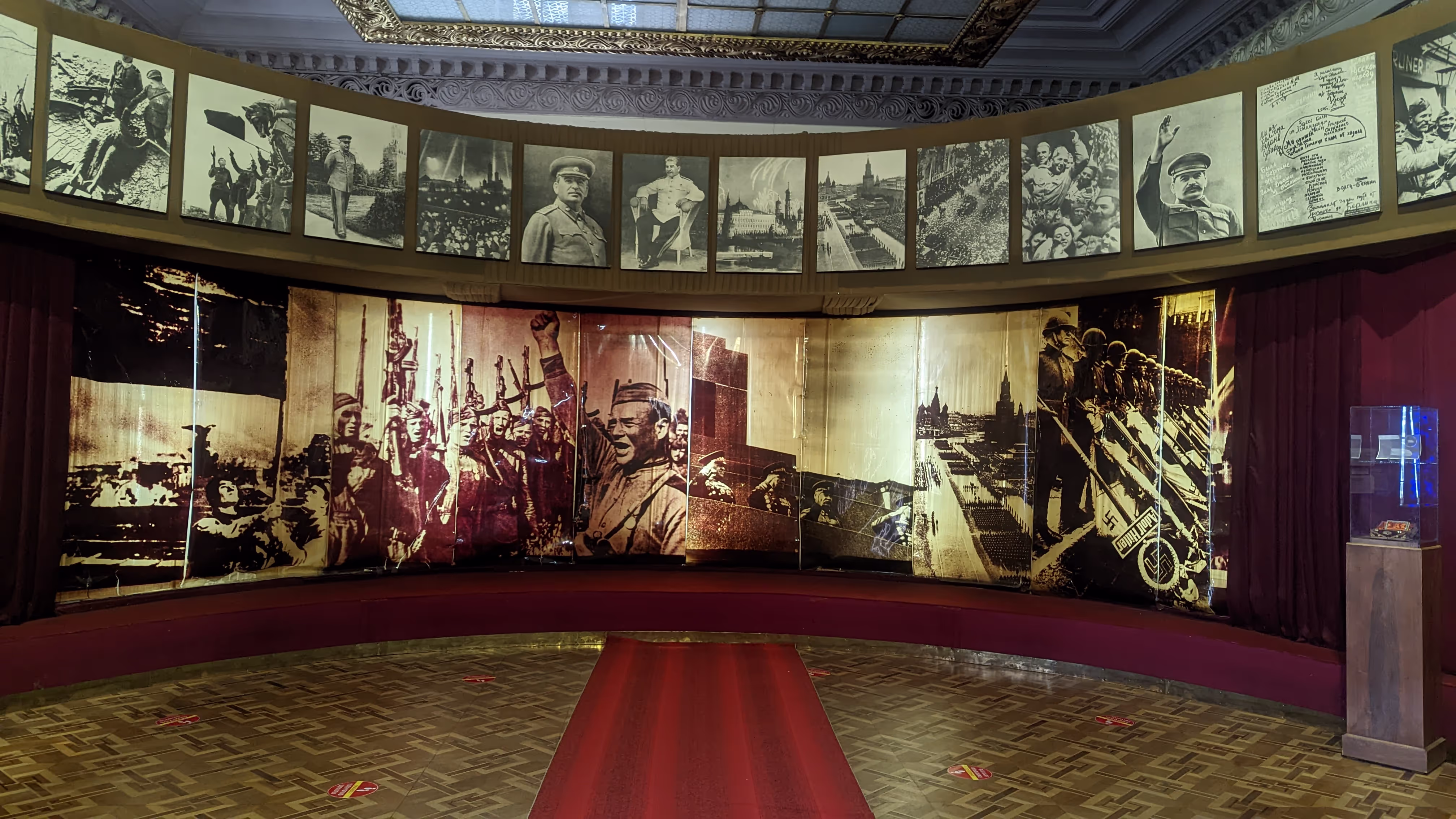 Soviet-era war exhibition inside the Stalin Museum in Gori, Georgia, featuring historical photos and propaganda murals.