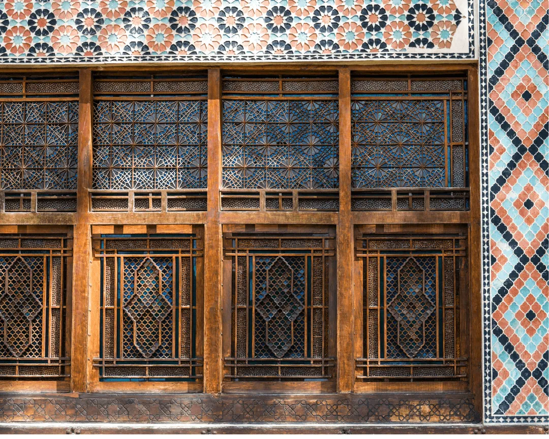 Ornate facade of Palace of Sheki Khans in Sheki, Azerbaijan, displaying intricate wooden latticework and tile patterns.
