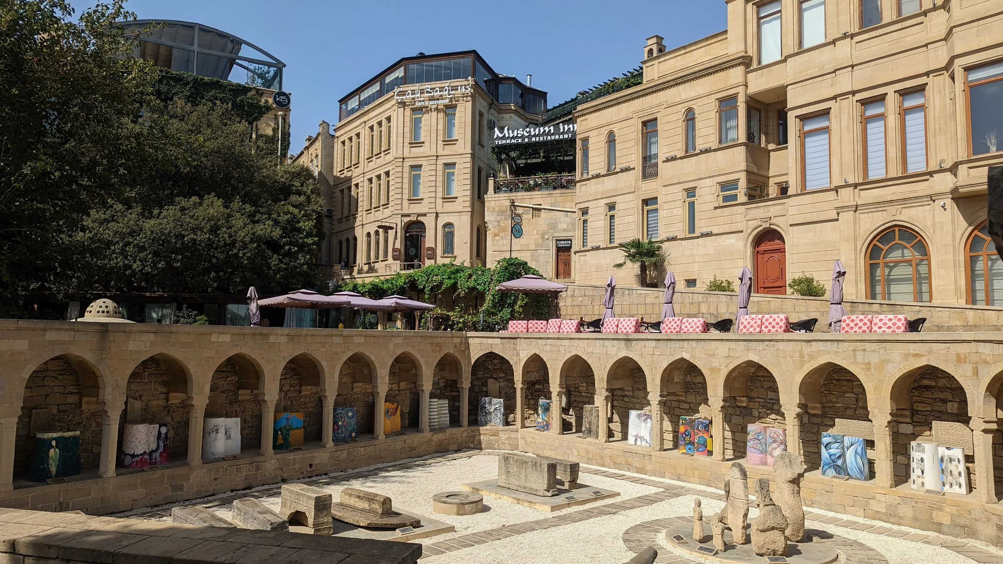 Baku Old Town, Azerbaijan, featuring arched stone walkways, modern terraces, and a vibrant outdoor art display.
