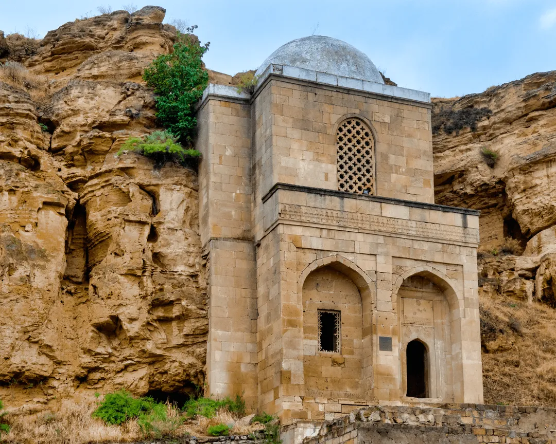 Diri Baba Mausoleum in Azerbaijan, an ancient stone tomb built in a rocky hillside with intricate Islamic architecture.