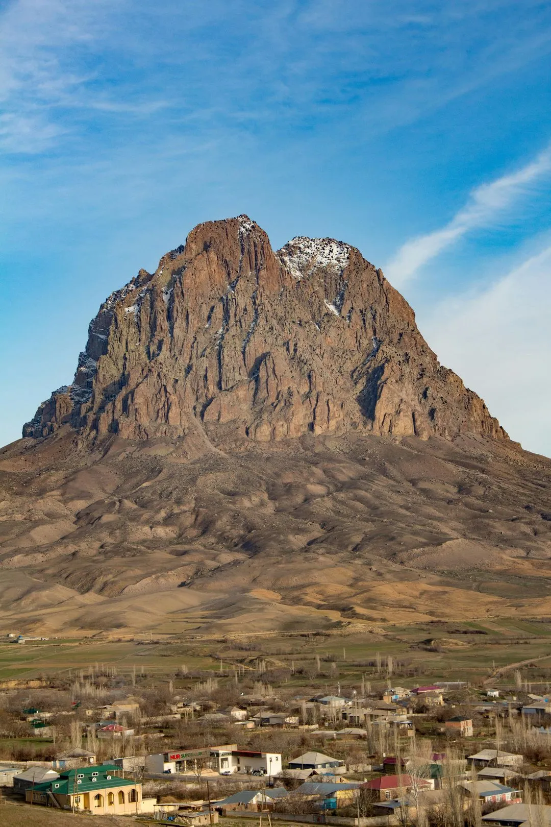 Majestic Ilan Dag mountain in Nakhchivan, Azerbaijan, with a village at its base and rugged cliffs.