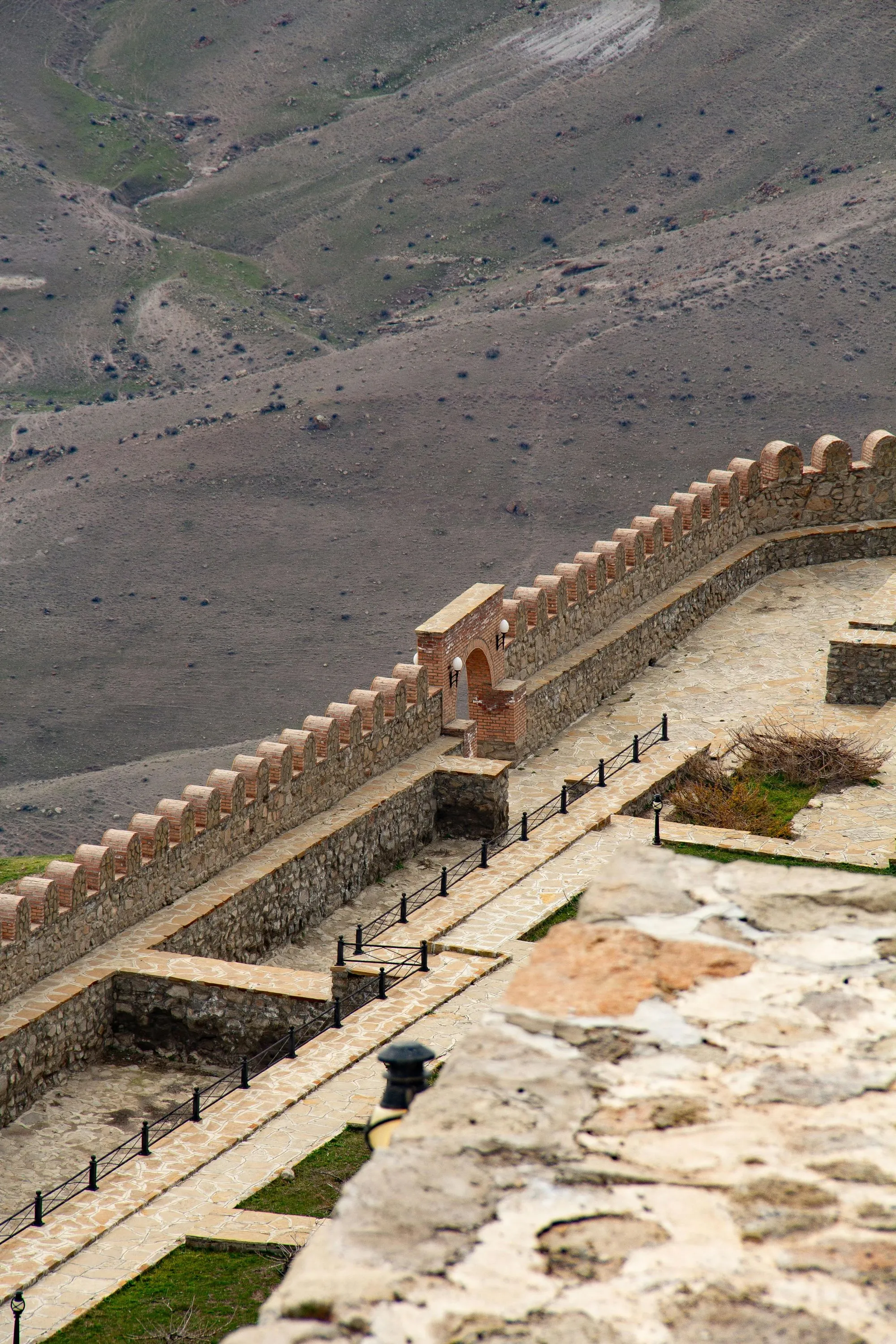 Ancient fortress walls in Azerbaijan, overlooking a vast, arid landscape with rugged terrain.
