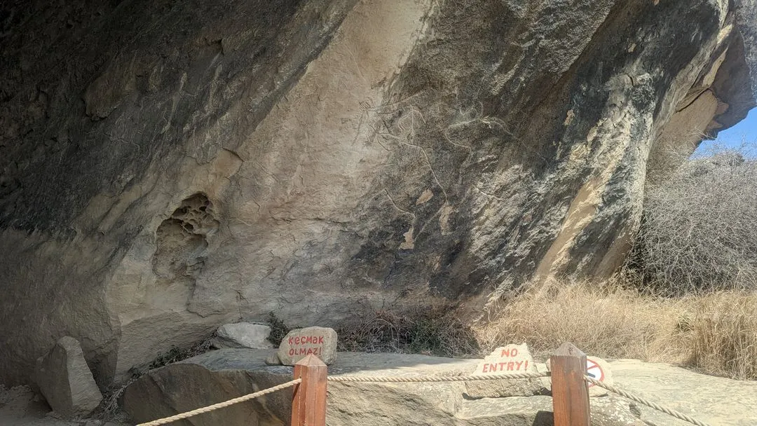 Gobustan petroglyphs in Azerbaijan, ancient rock carvings of animals and human figures on a weathered stone surface.