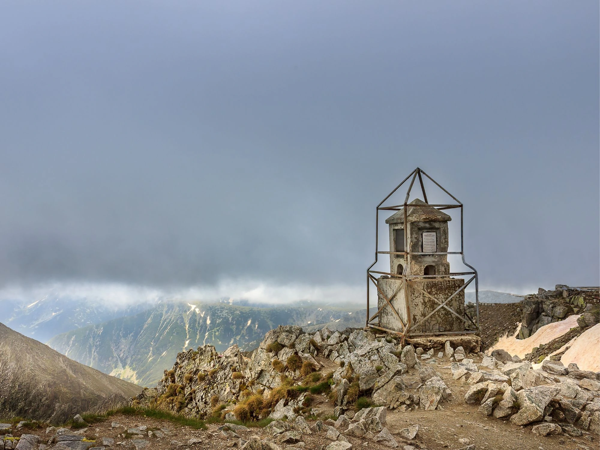 Summit of Musala Peak, Bulgaria’s highest mountain, with a historic weather station framed by dramatic clouds.