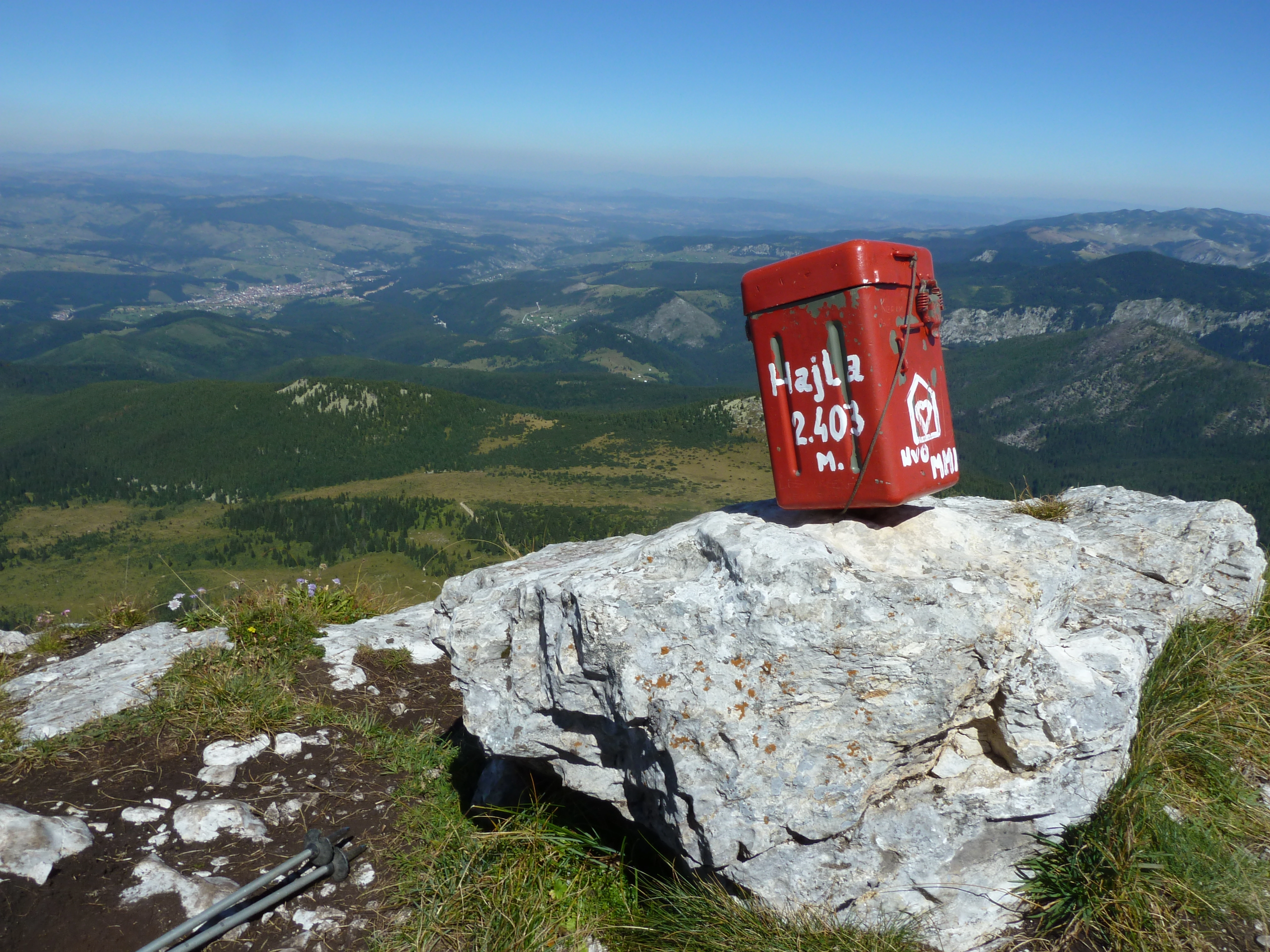 A red summit box atop Mount Hajla (2,403m), offering panoramic views over the rolling green valleys below.