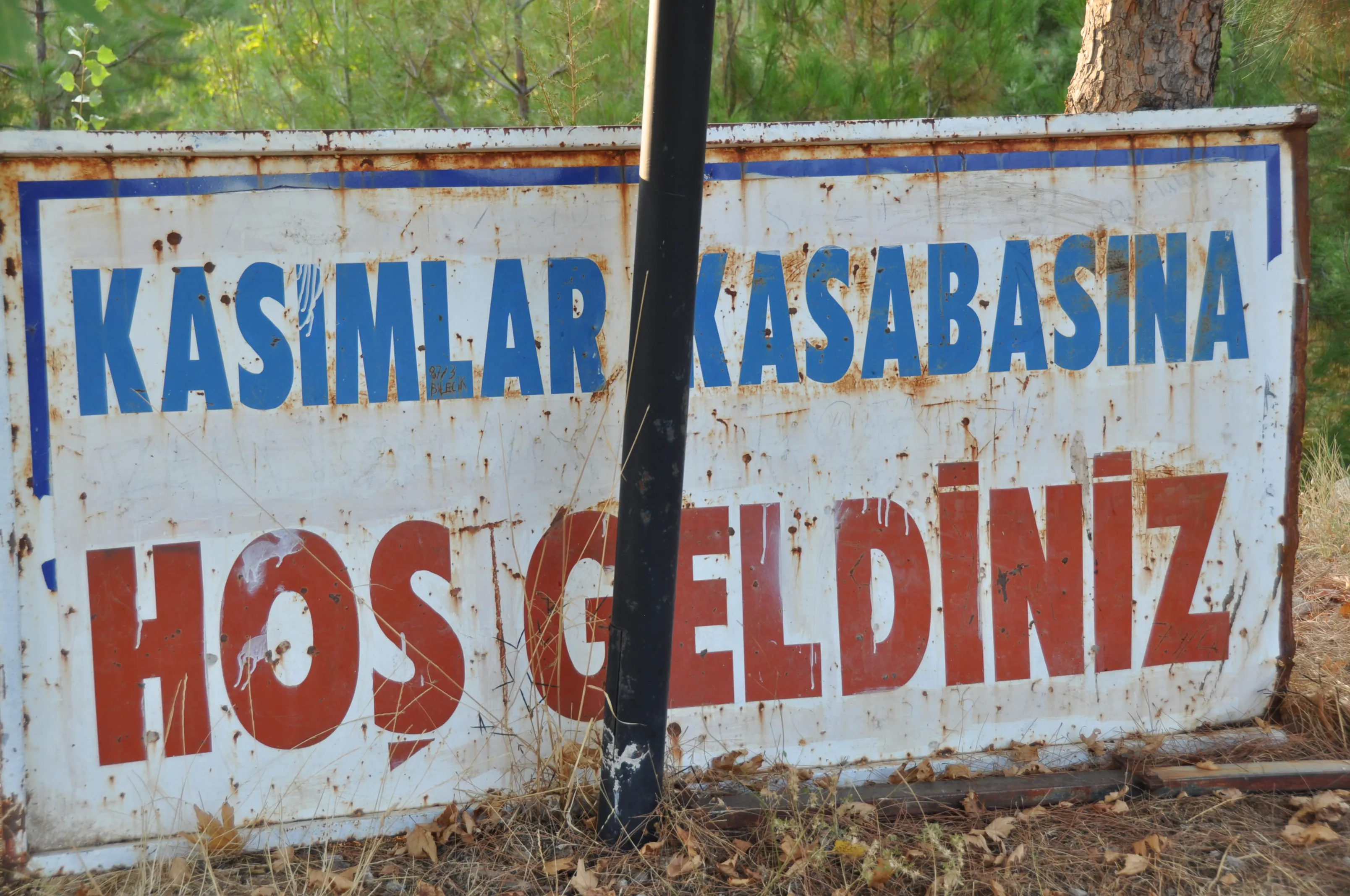 Welcome Sign – A weathered sign with Turkish text welcomes visitors to the town of Kasım lar on the St. Paul Trail.