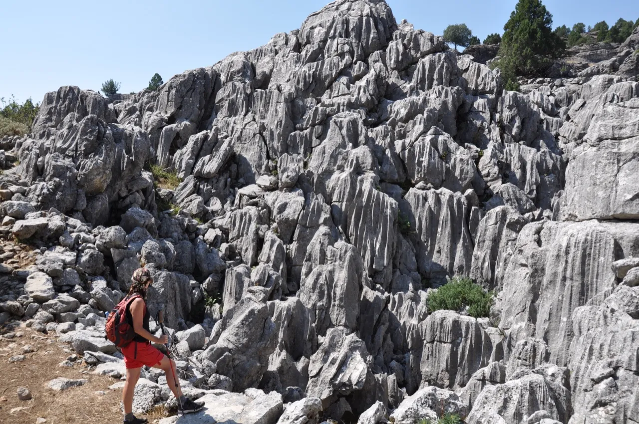 A hiker in red shorts looks up at jagged rock formations on the St. Paul Trail.
