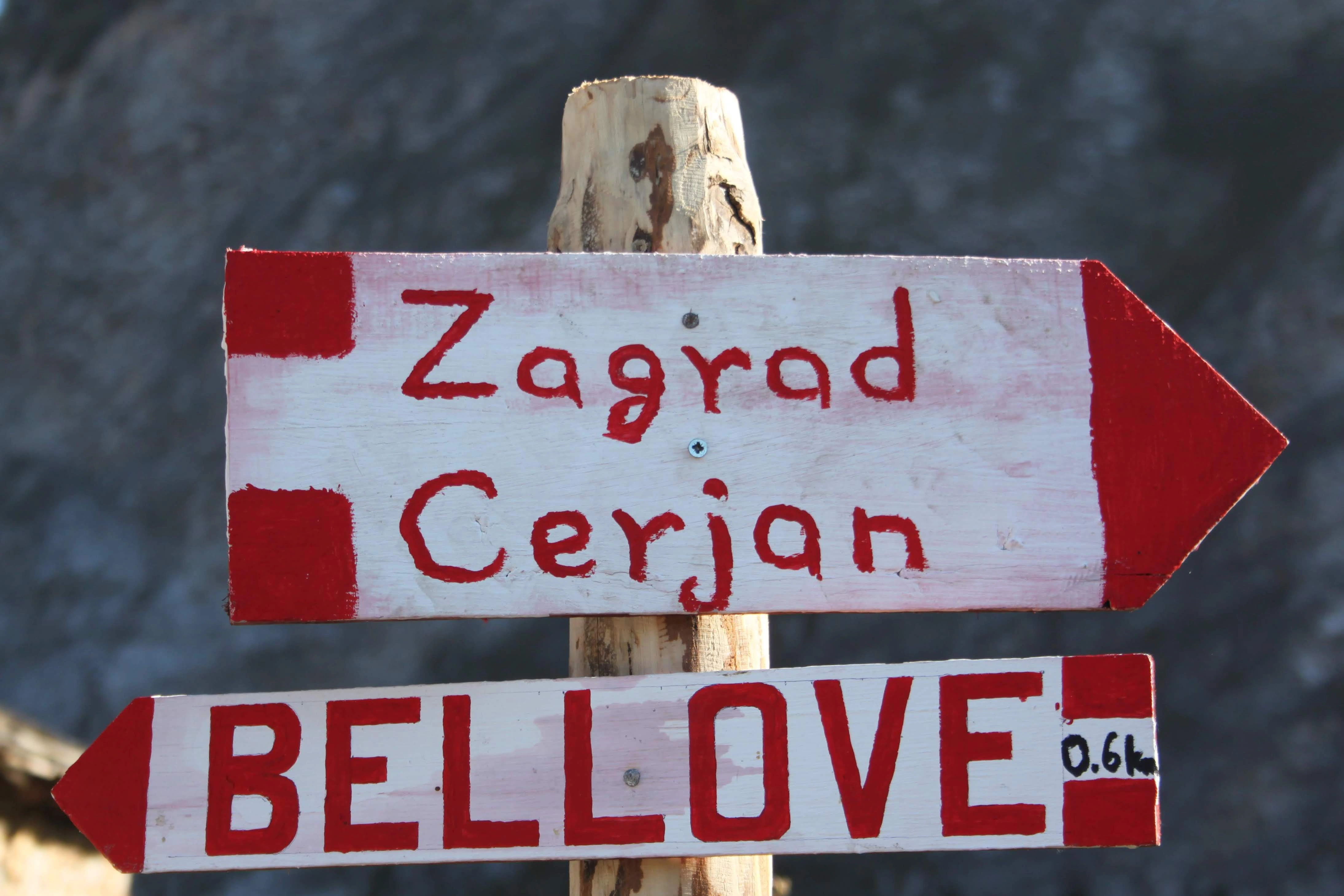 Trail sign near Bellove – A wooden signpost with red arrows marks trails to Zagrad Cerjan and Bellove in High Scardus.