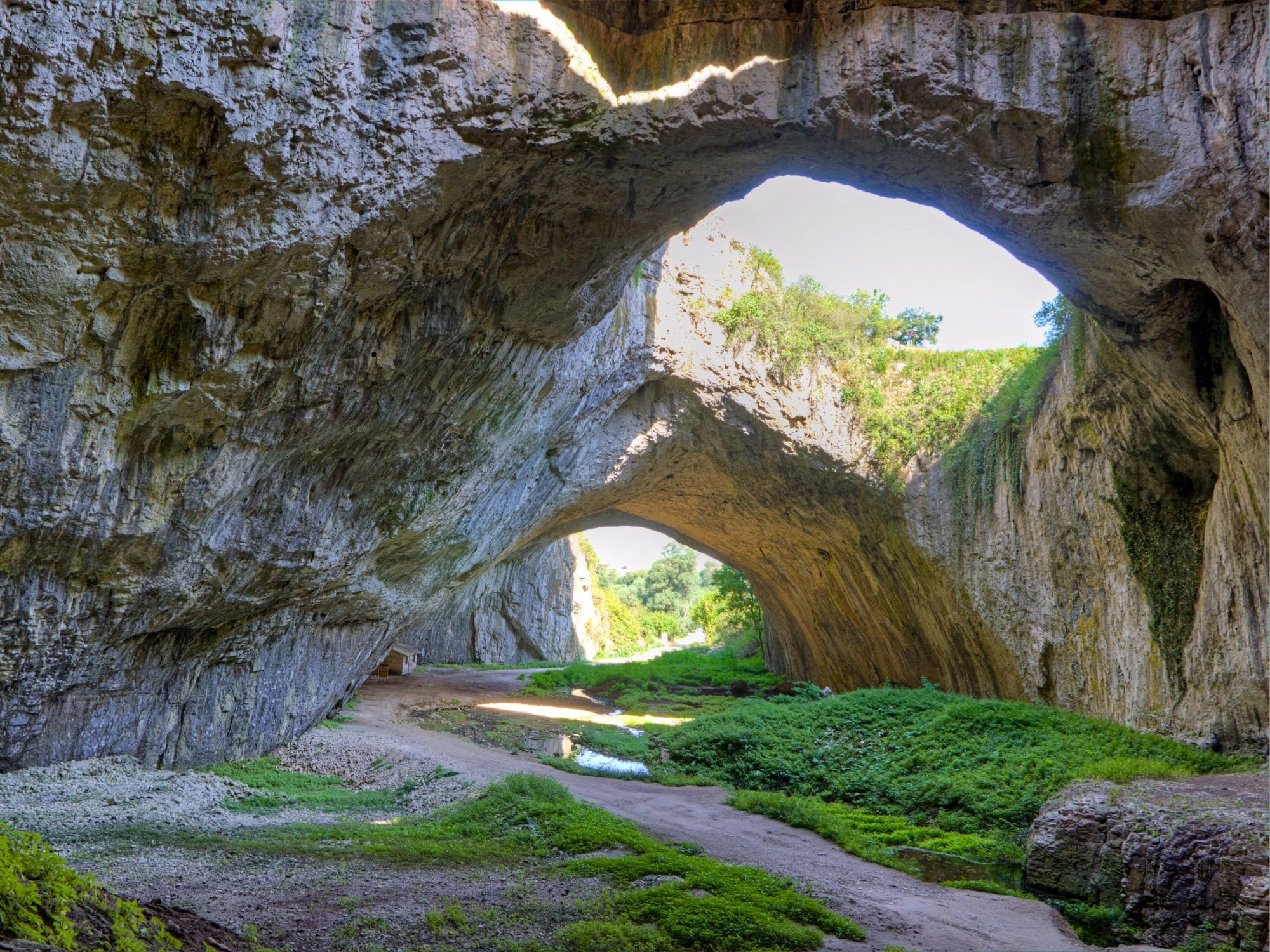 Devetashka Cave in Bulgaria - The stunning Devetashka Cave with massive rock arches and lush greenery inside.