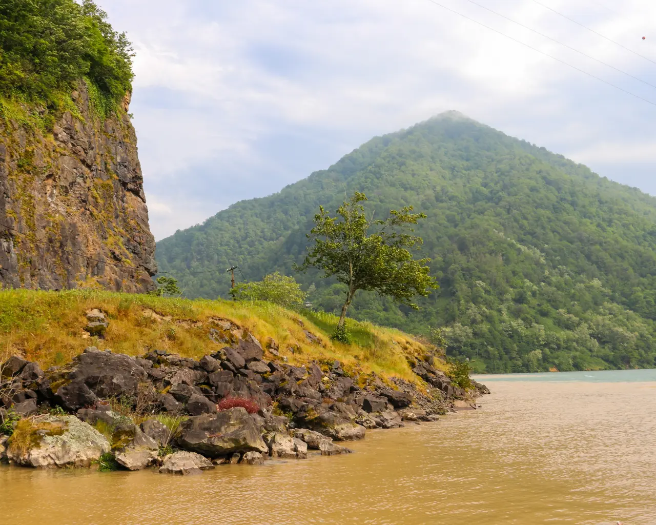 A misty mountain landscape in Adjaristskali, Georgia, with rugged cliffs and a serene lake nestled between the peaks.