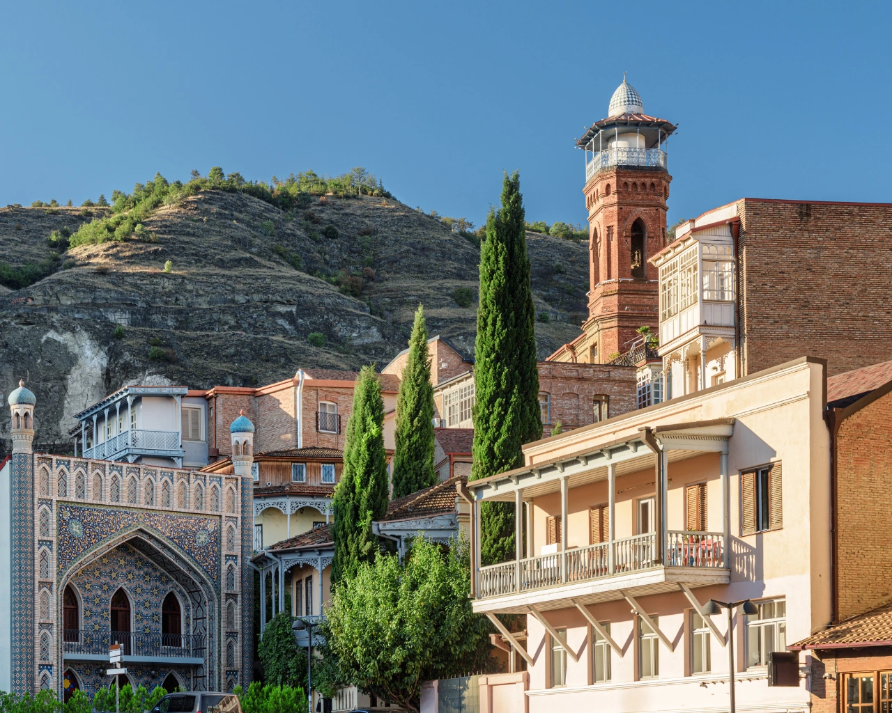 Old Town Tbilisi with Juma Mosque and colorful buildings set against a rocky hillside.