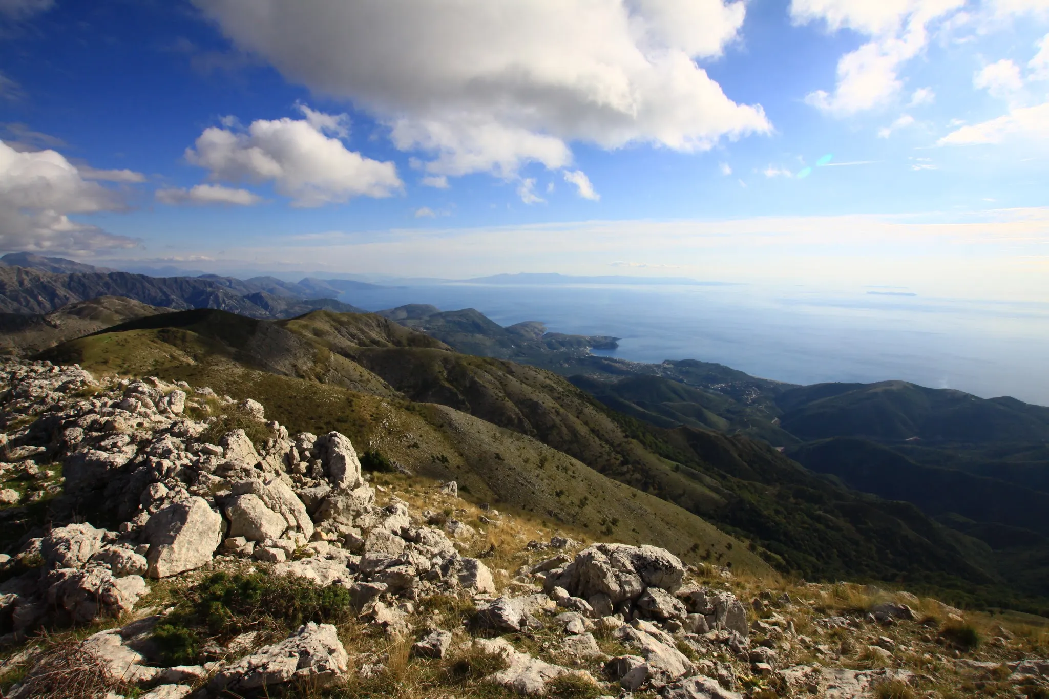 Rocky mountain peaks with rolling green hills and a breathtaking view of the coastline from a hiking trail.