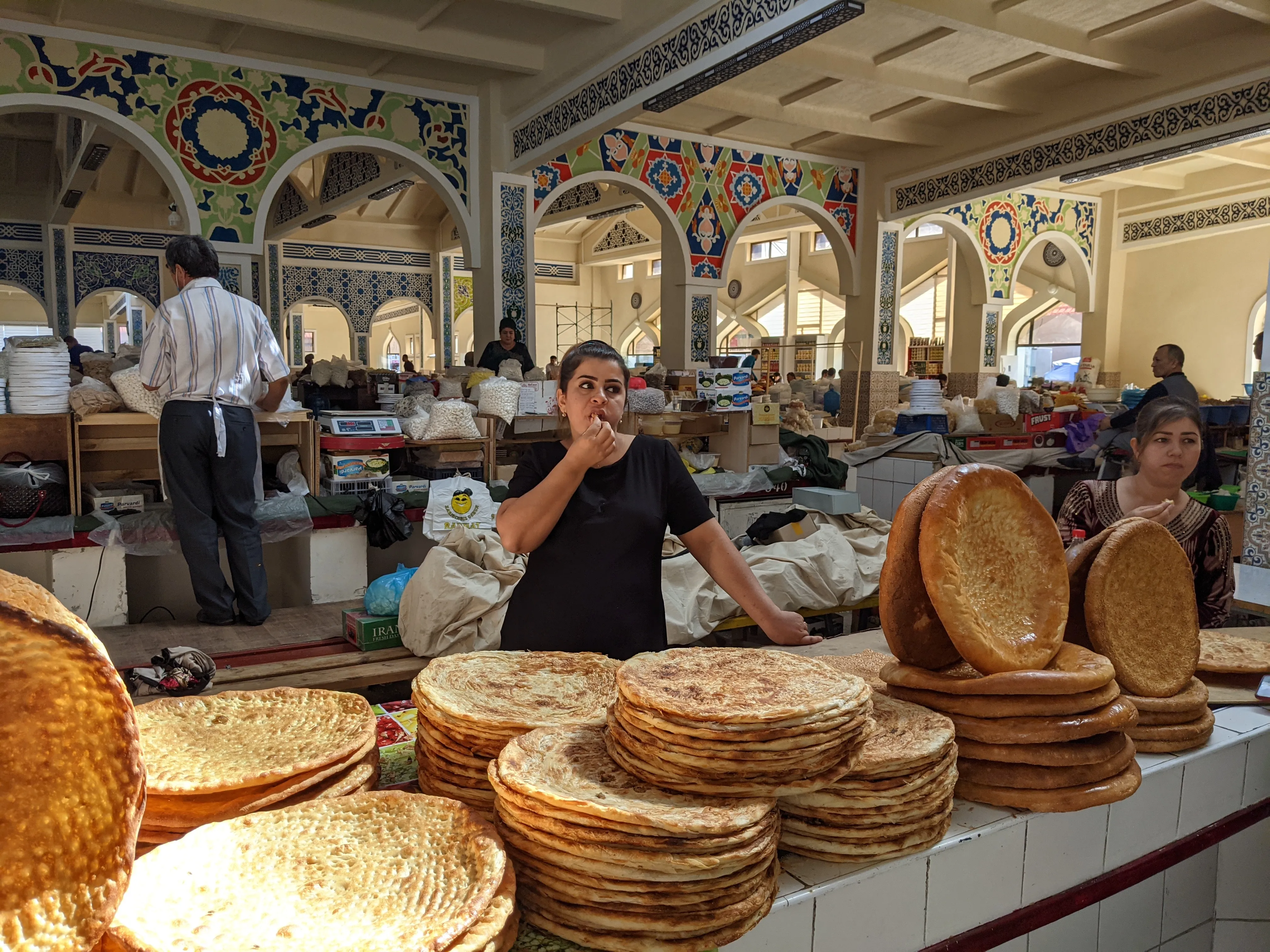 A woman selling fresh Uzbek non bread at a bustling local market.