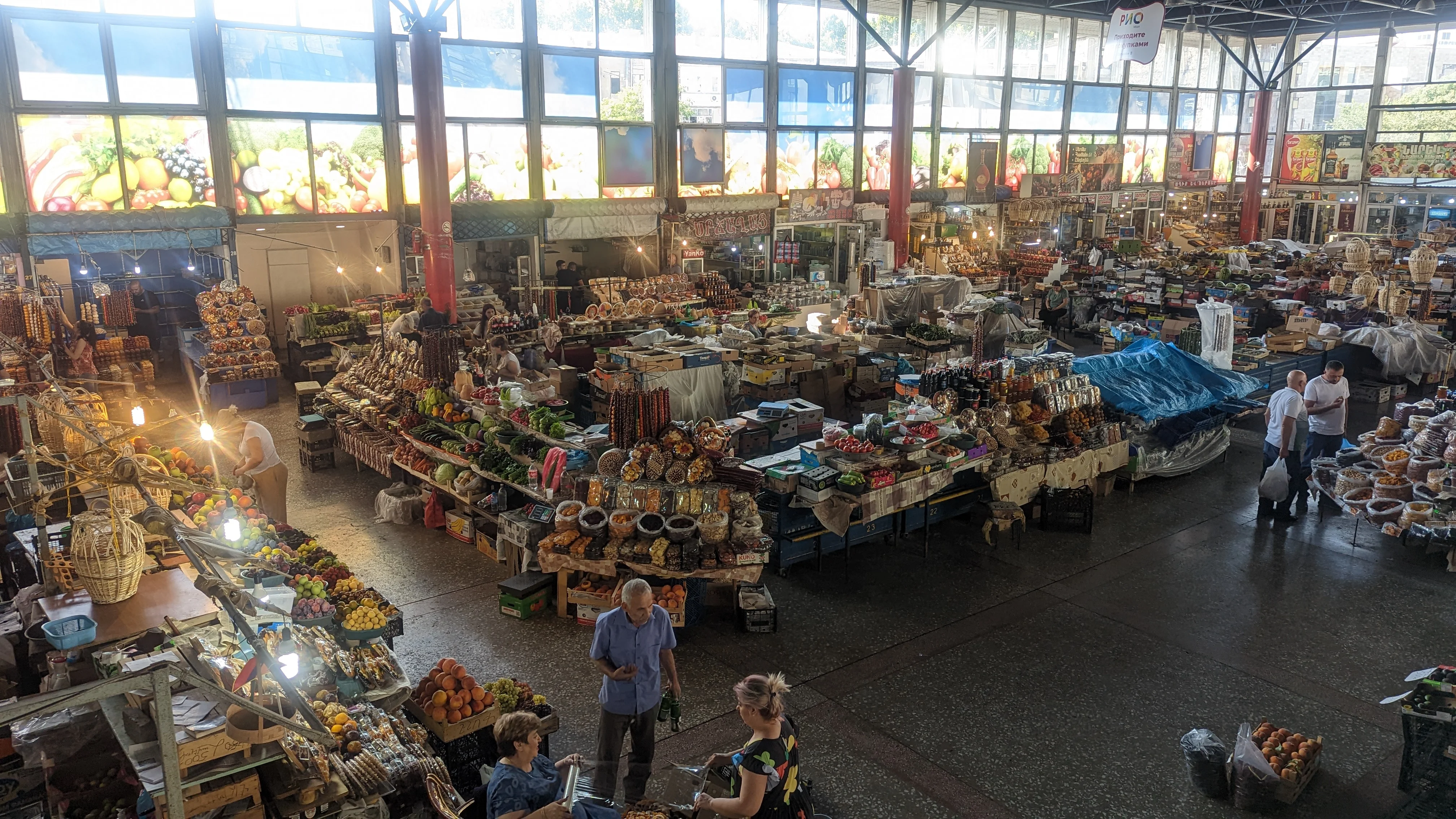 Busy indoor market in Yerevan with fresh produce, spices, and locals shopping.