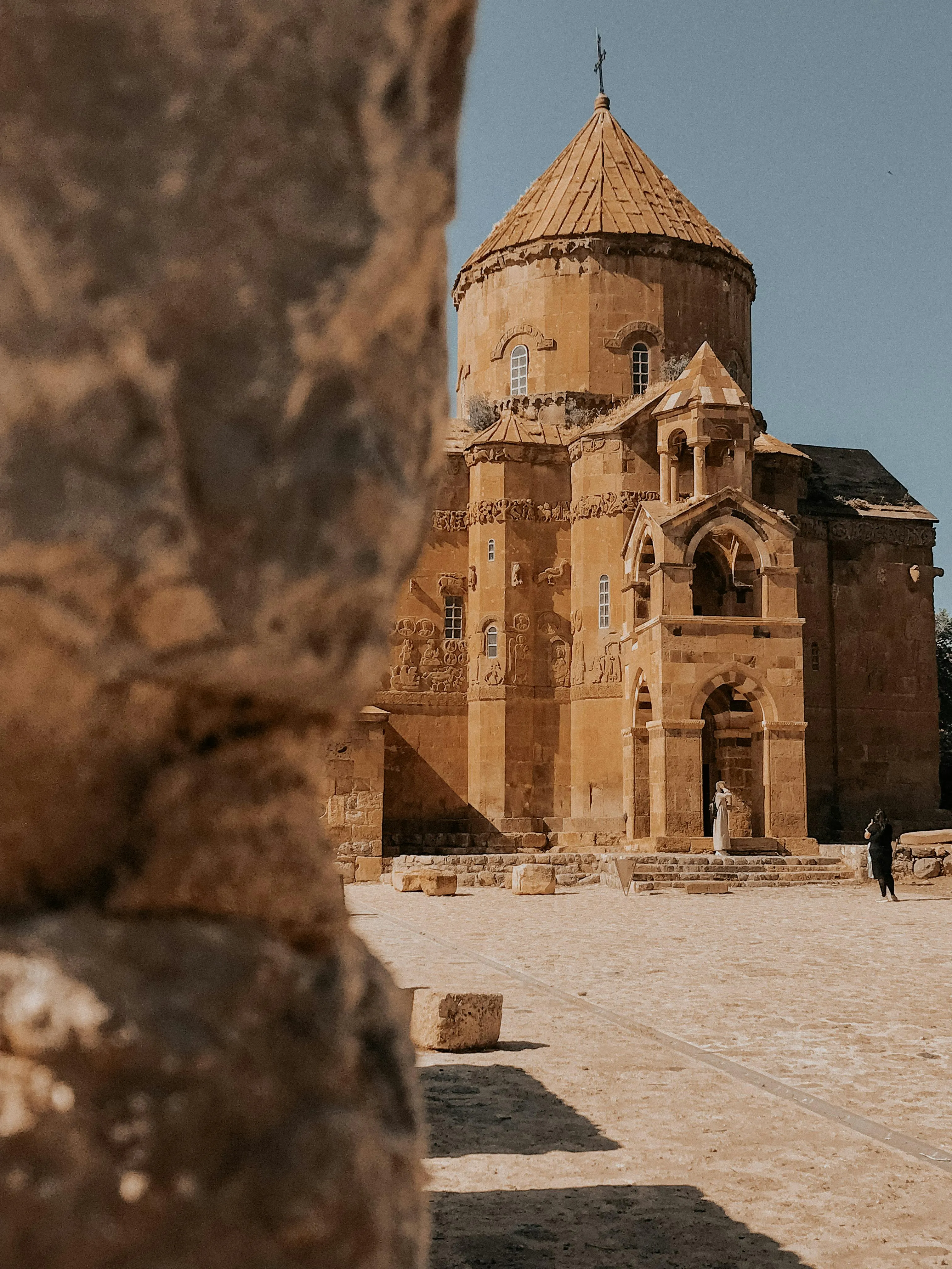 An ancient Armenian church with intricate carvings, framed by a weathered stone.