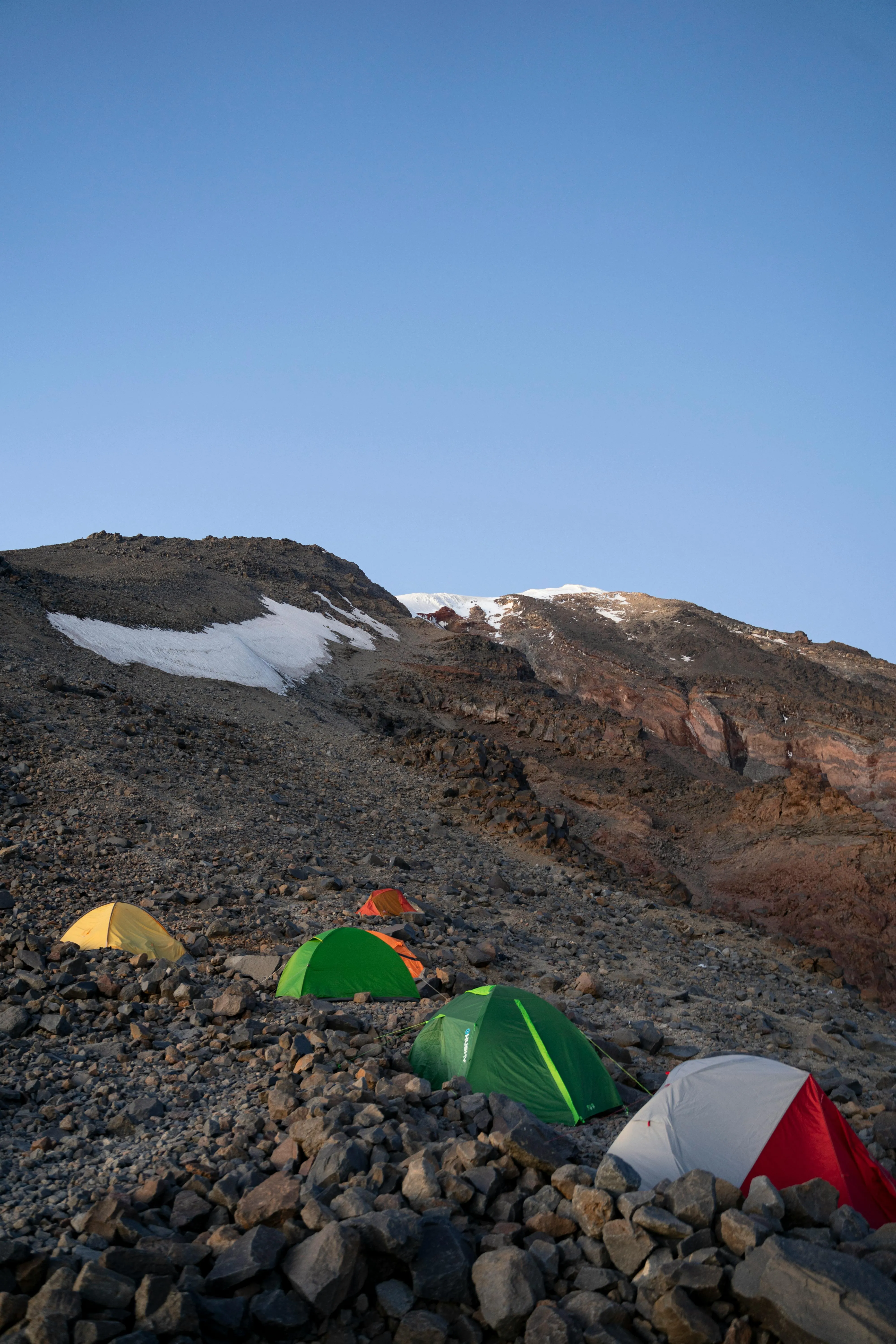 A high-altitude campsite on Mount Ararat, with colorful tents on rocky terrain.