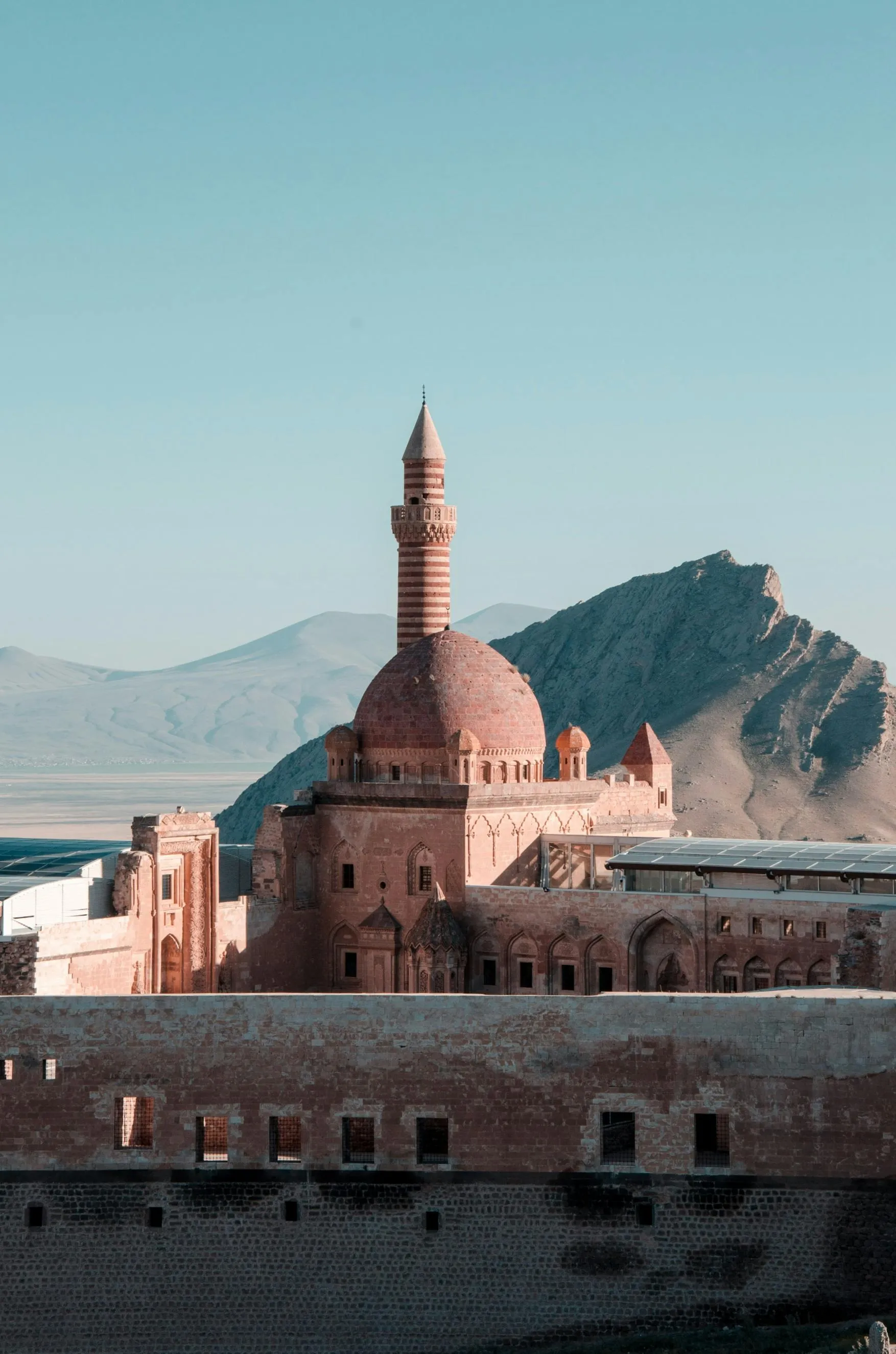 Ishak Pasha Palace with its ornate dome and minaret, set against rugged mountains.