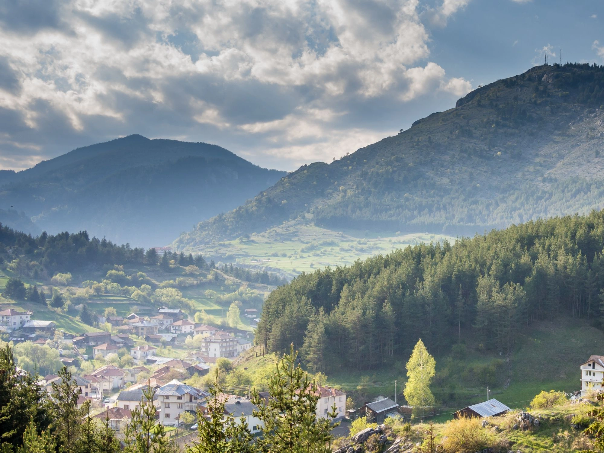 Village of Yagodina in a green valley, with terracotta rooftops nestled among forested hills.