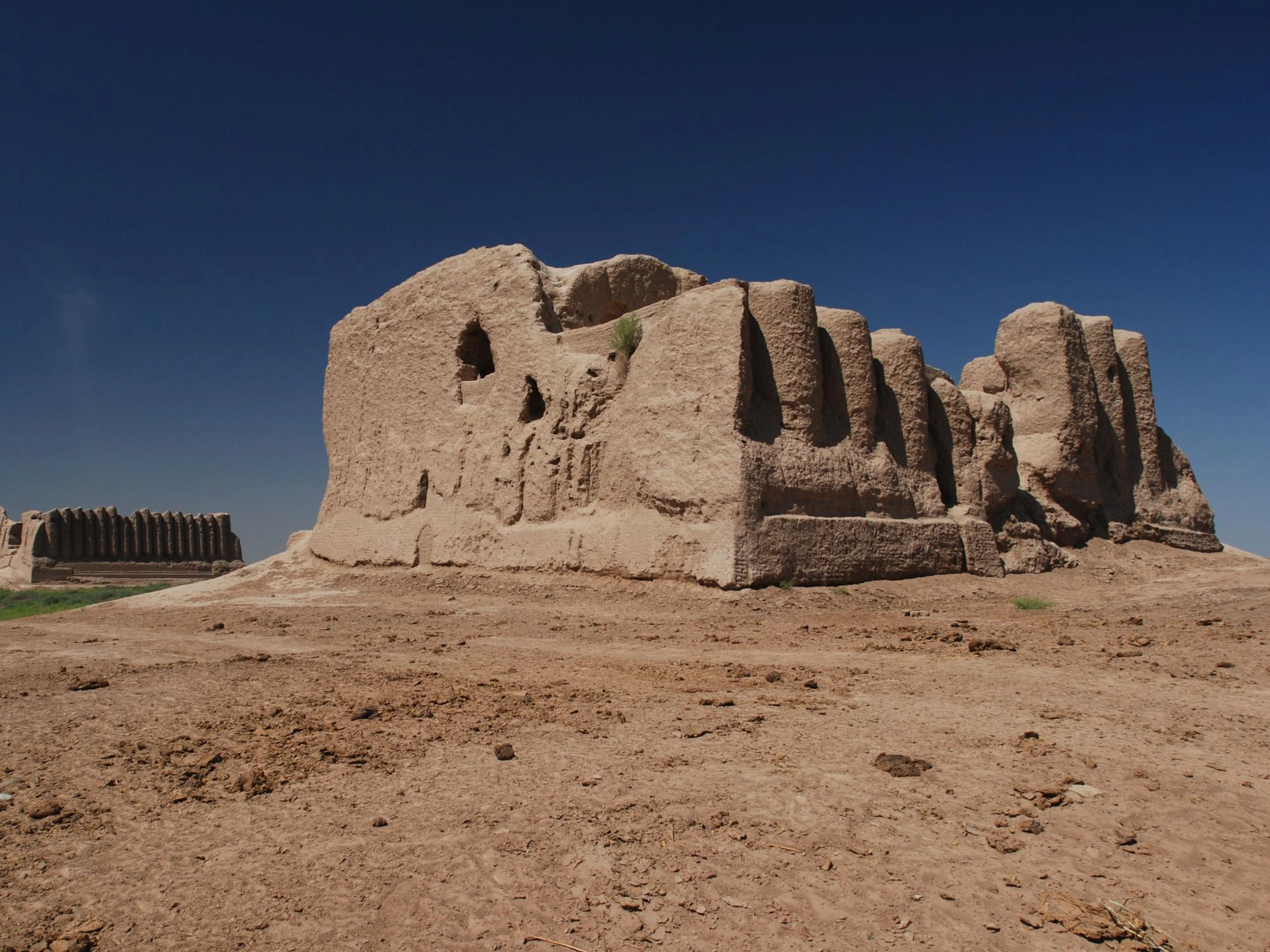 Ancient mudbrick ruins in Merv, Turkmenistan, standing against a clear blue desert sky.