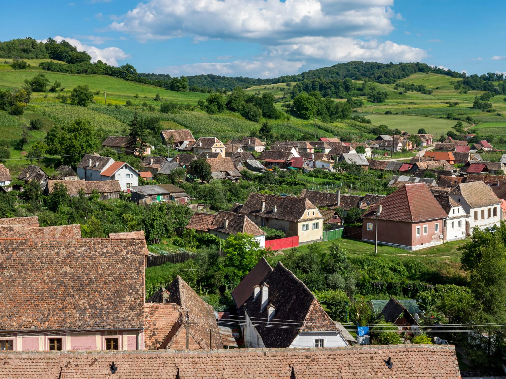 Aerial view of Biertan village with traditional houses and rolling green hills in Romania