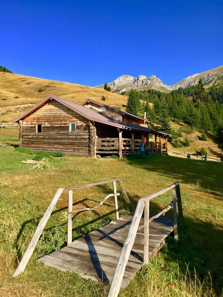 Rustic wooden guesthouse along the Via Dinarica trail in Kosovo, set in a scenic alpine meadow.