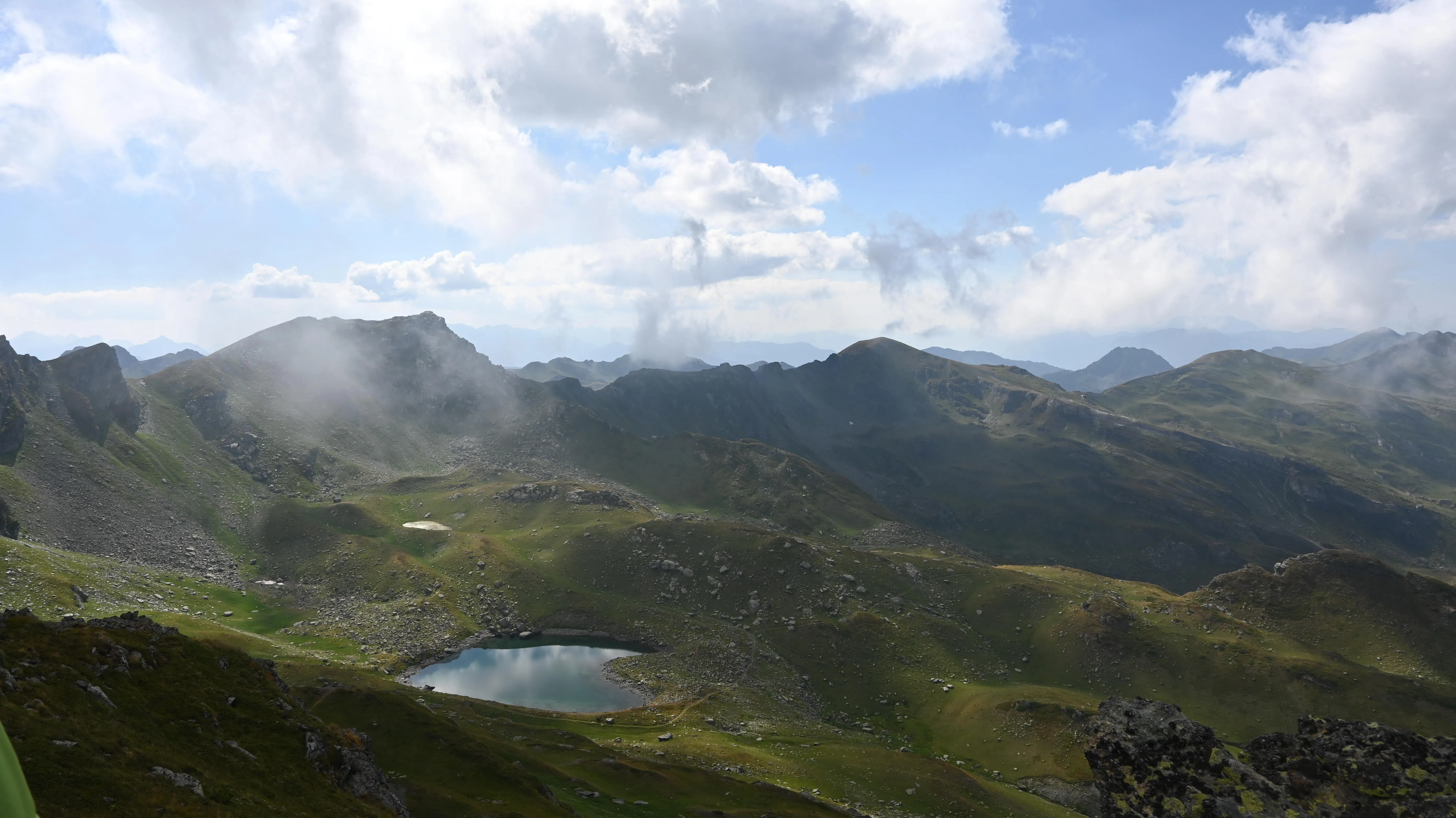 Heart-shaped mountain lake reflecting blue skies, surrounded by grassy slopes along Kosovo’s Via Dinarica