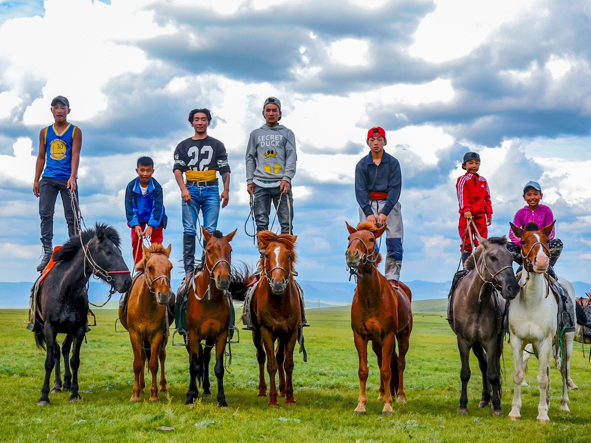 A group of Mongolian children standing on horseback, highlighting horsemanship culture during family travel.