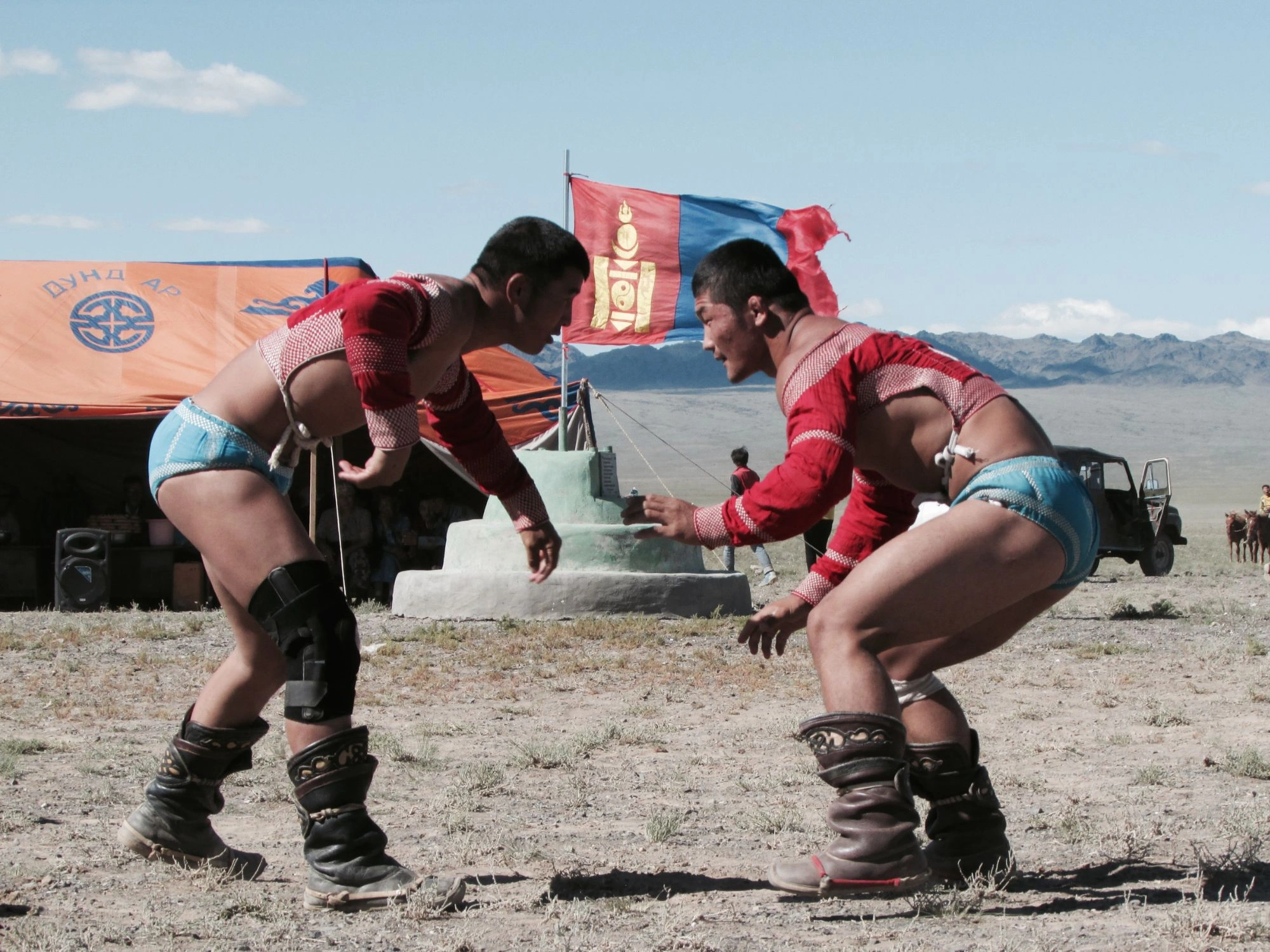 Elder and younger Mongolian locals in colorful deels sit on the grasslands, showcasing traditional culture and heritage.