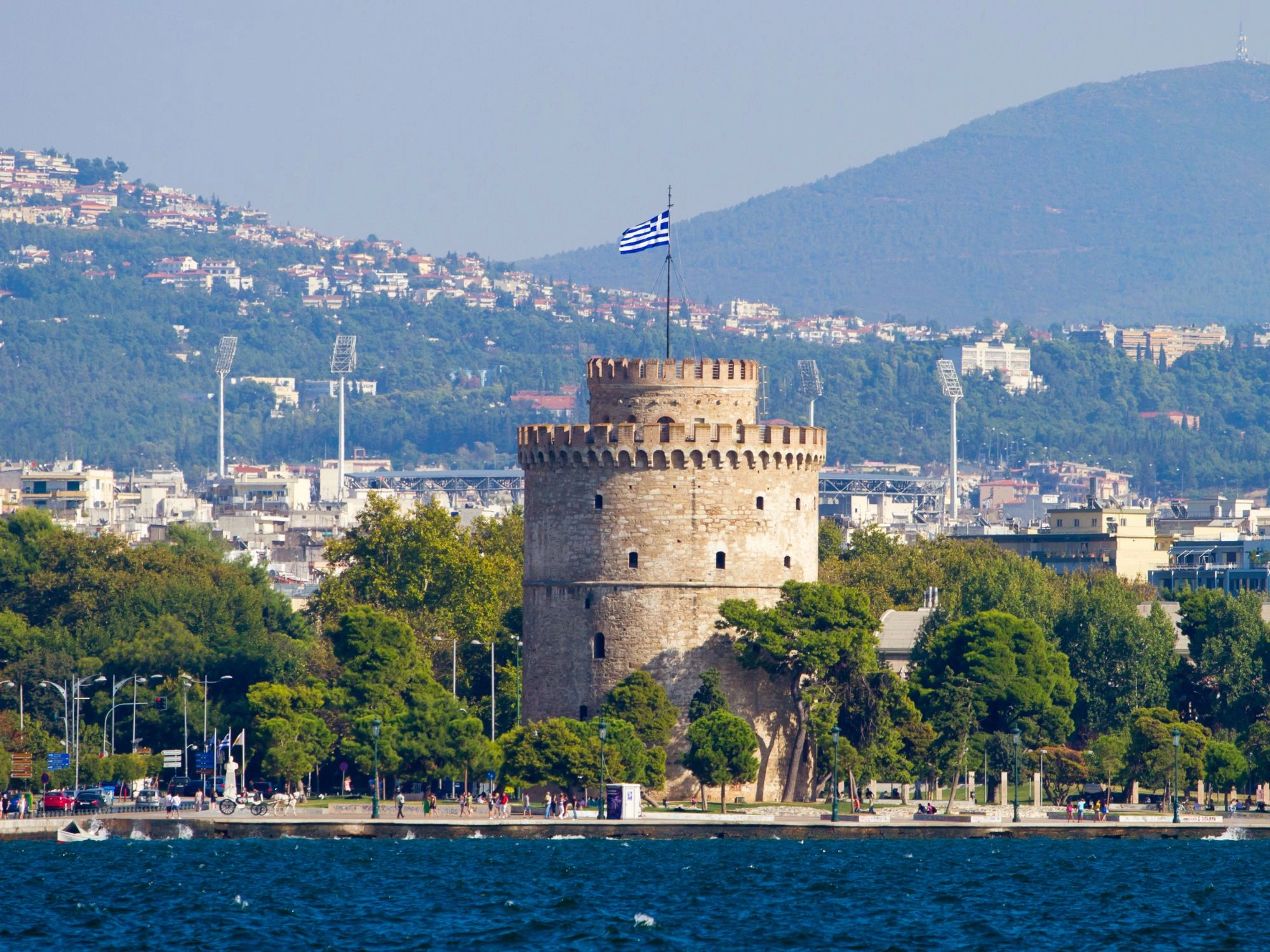White Tower of Thessaloniki with Greek flag, a famous seafront landmark in Greece.