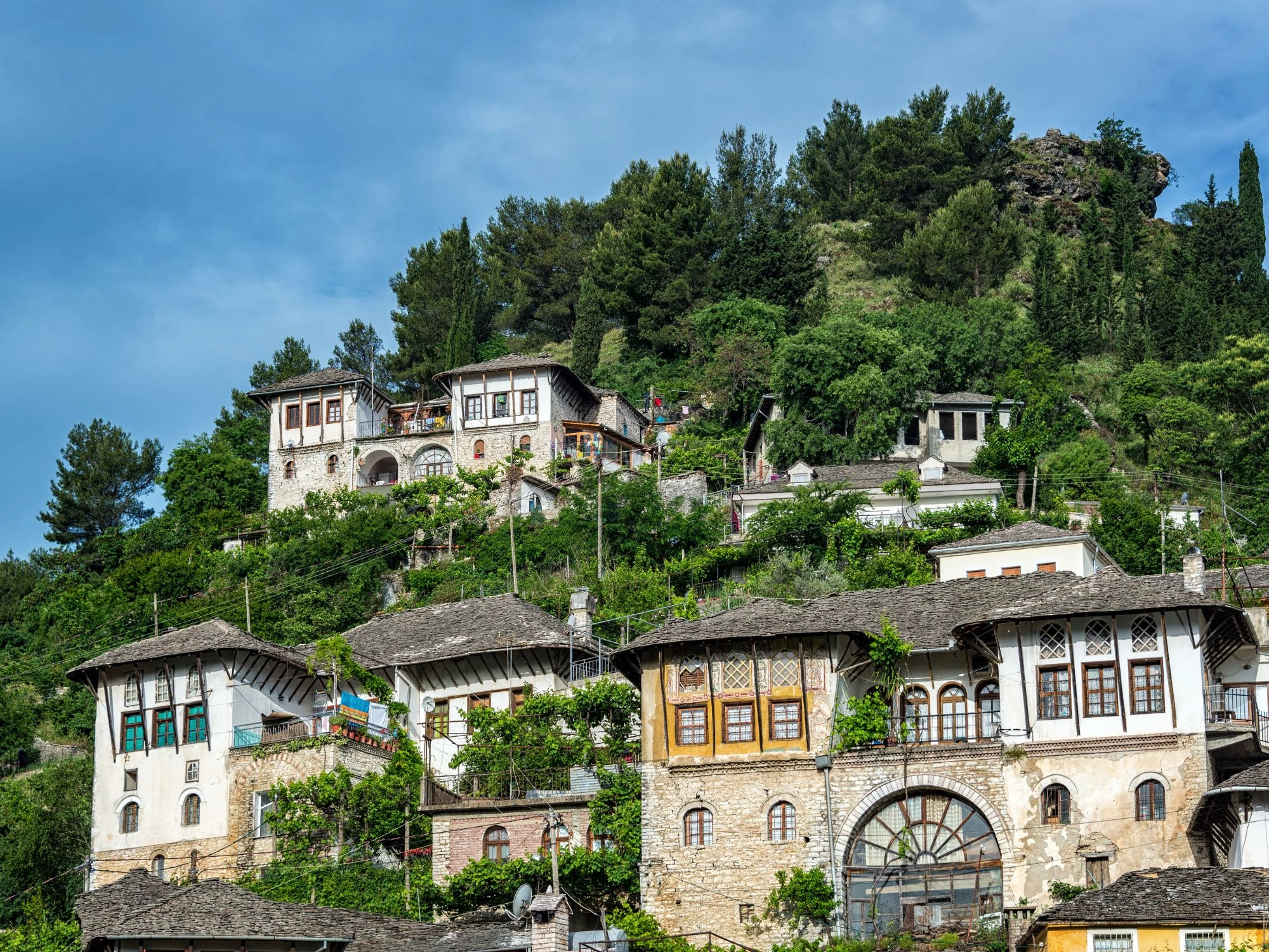 Traditional Ottoman-style houses on a green hillside in Gjirokastër, Albania, a UNESCO heritage site.