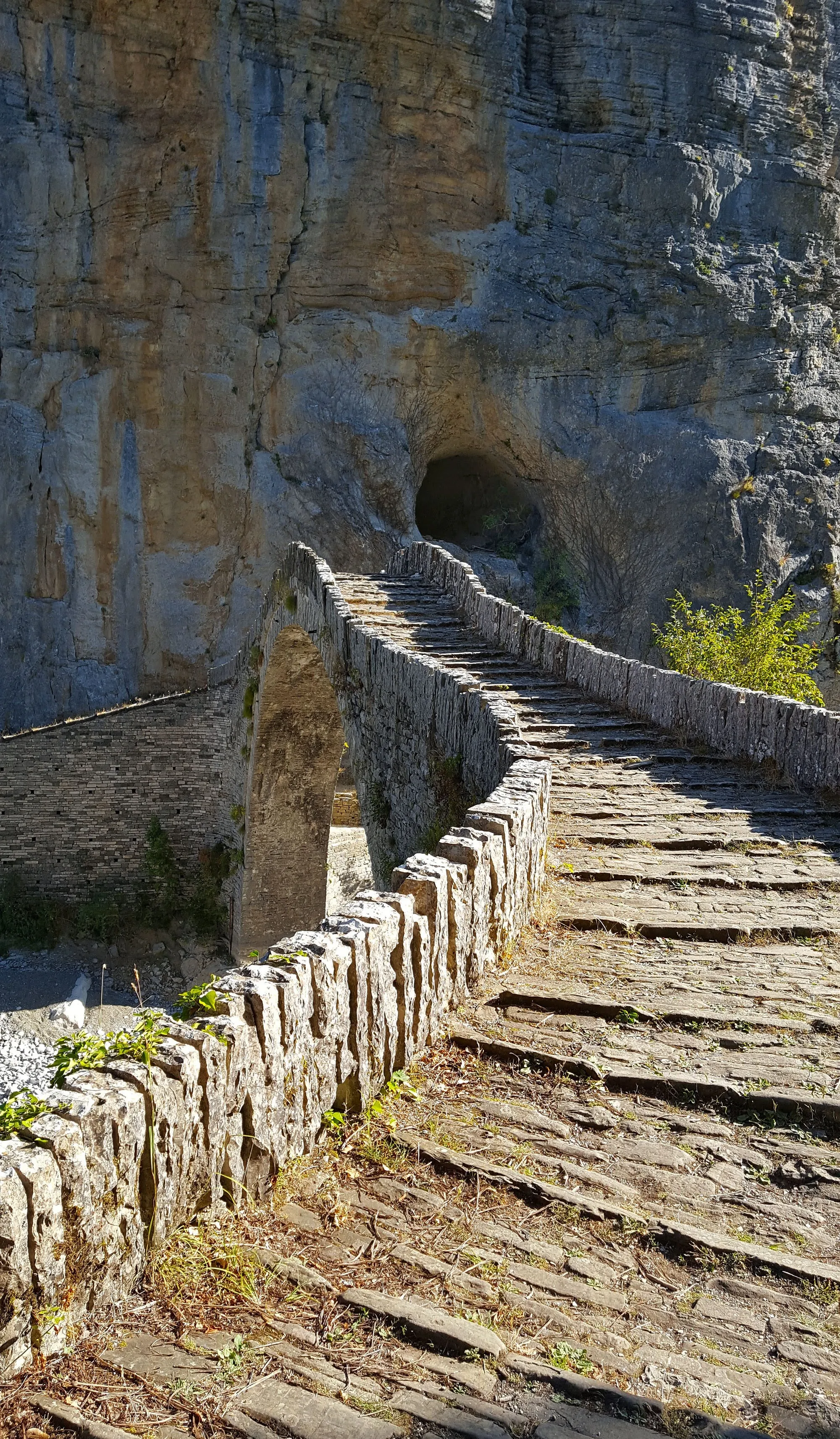Historic stone arch bridge set against towering rock cliffs near the village of Kokkori in Epirus.