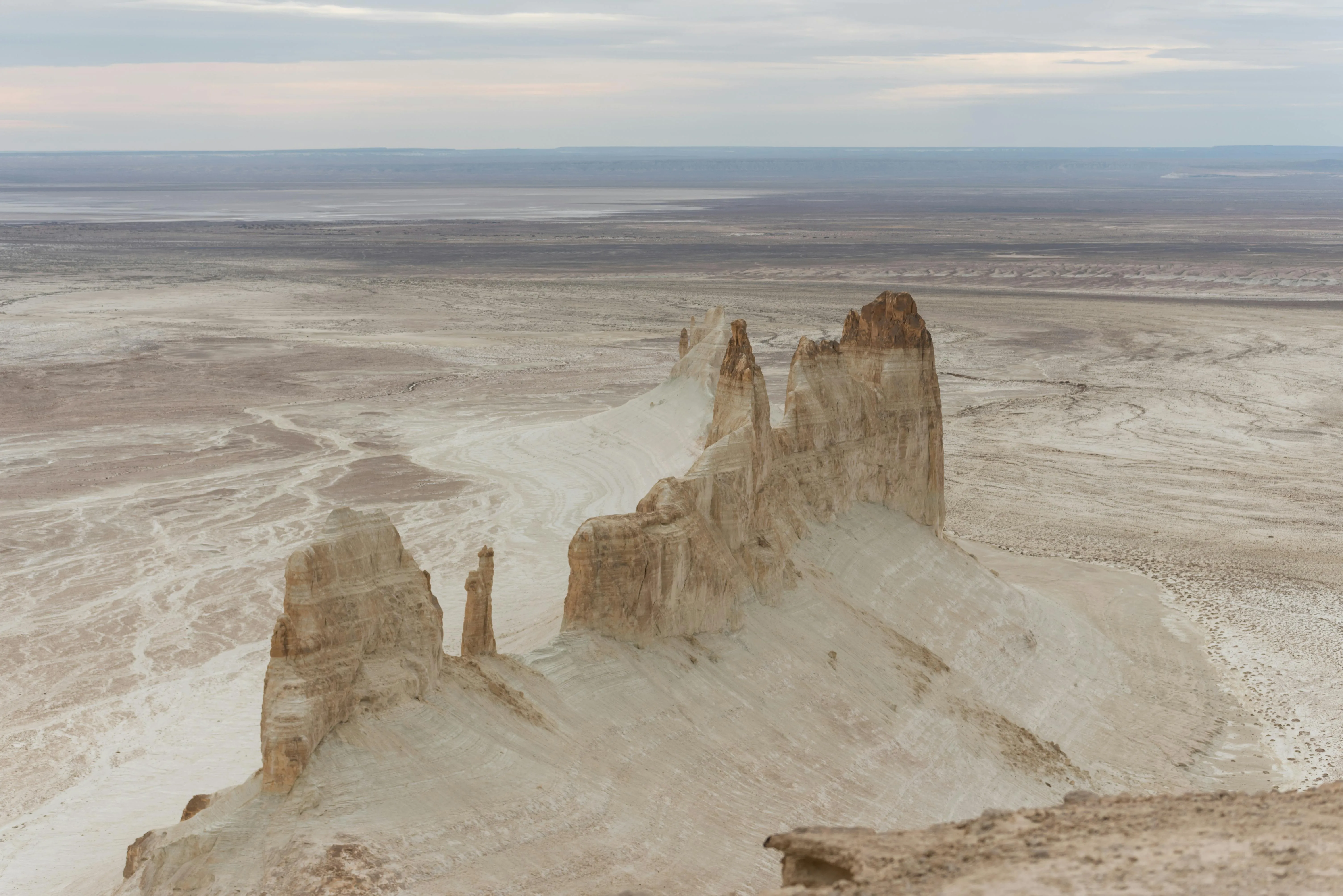 Dramatic white rock formations tower above the Mangystau desert, showcasing Kazakhstan’s raw natural beauty.