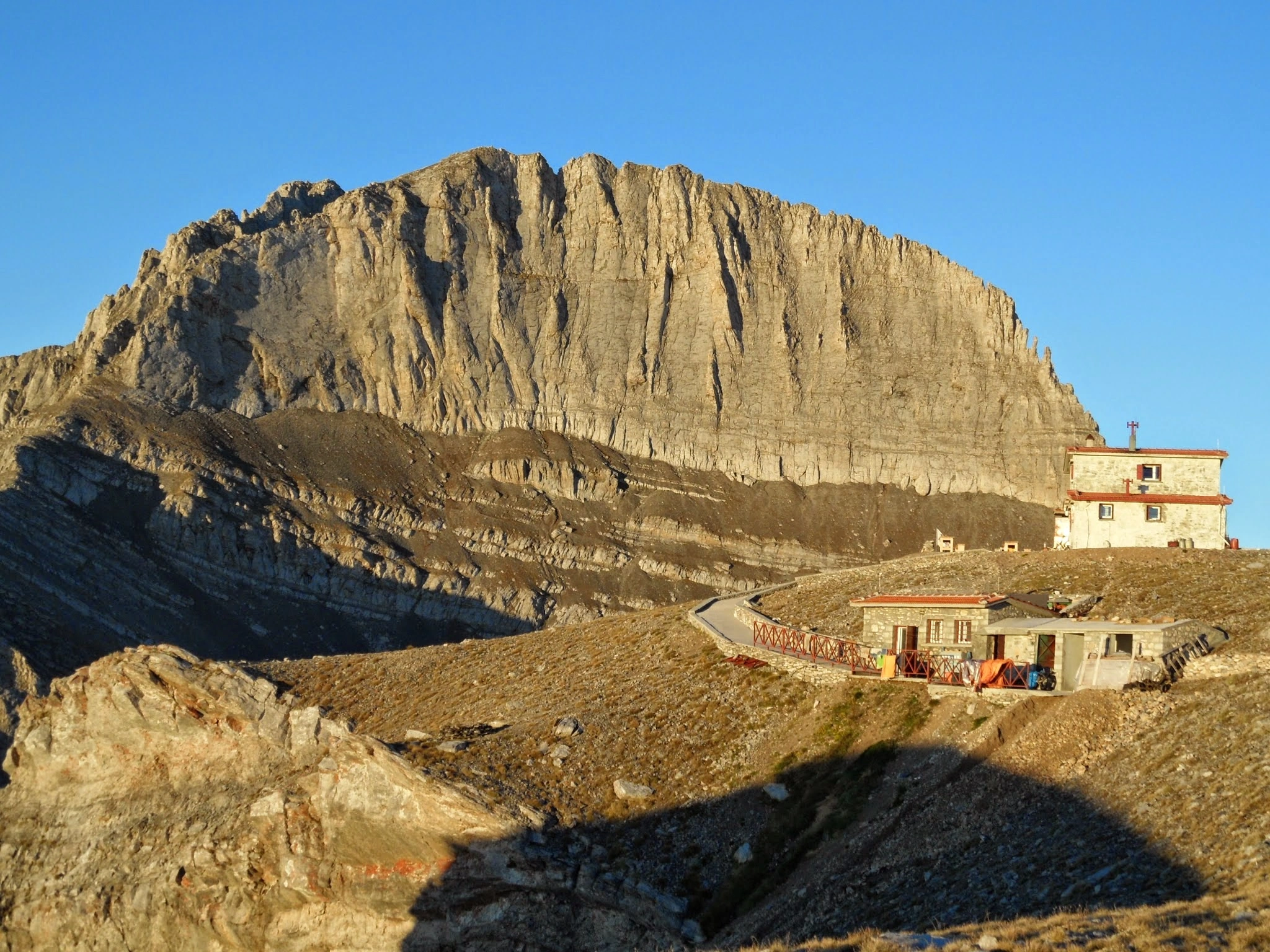 Kakalos Mountain Hut on Mount Olympus, Greece, with Stefani Peak, known as the Throne of Zeus, in the background.