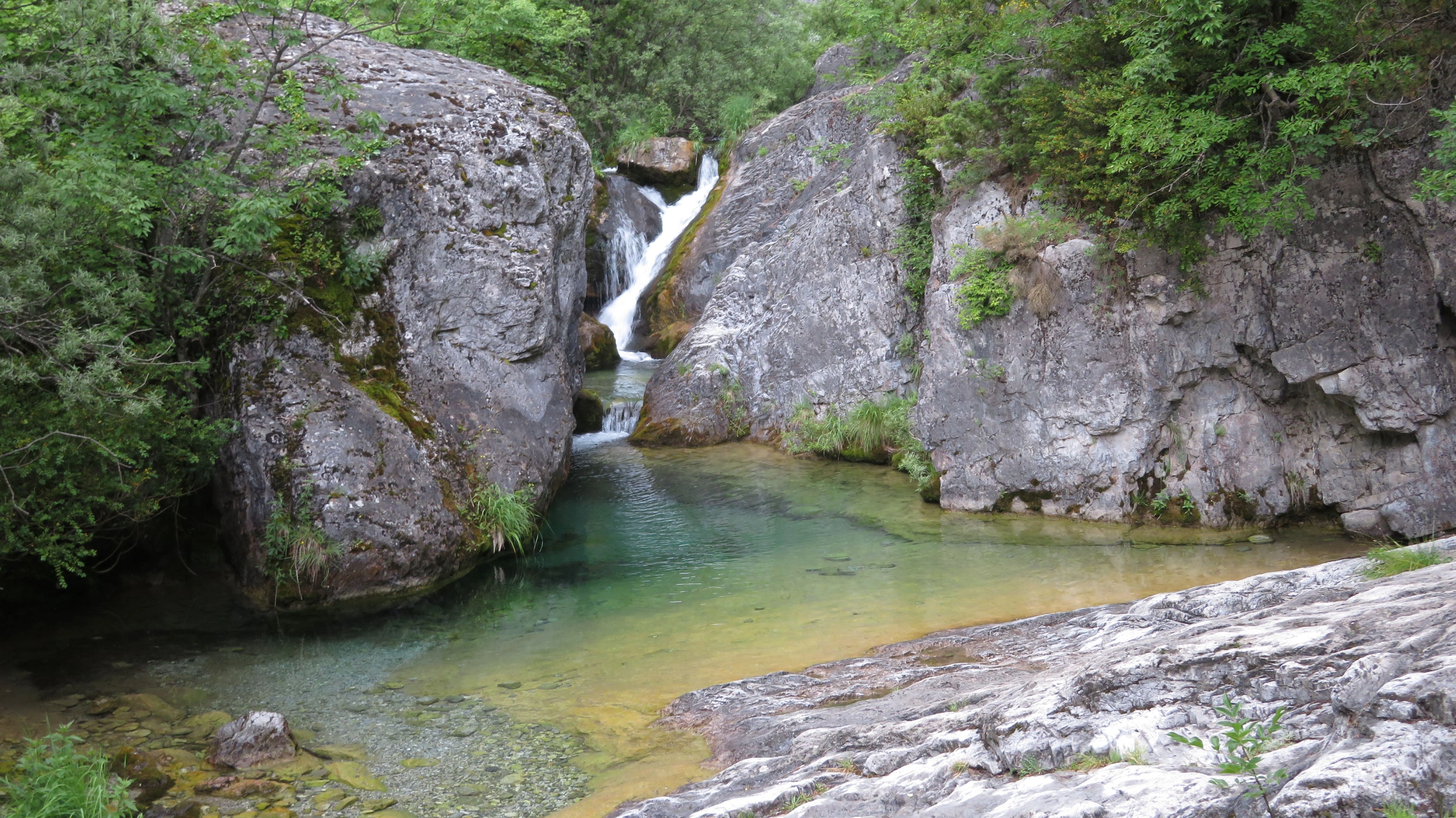 Scenic view of a crystal-clear waterfall and natural pool in Enippeus Gorge, Mount Olympus National Park, Greece.