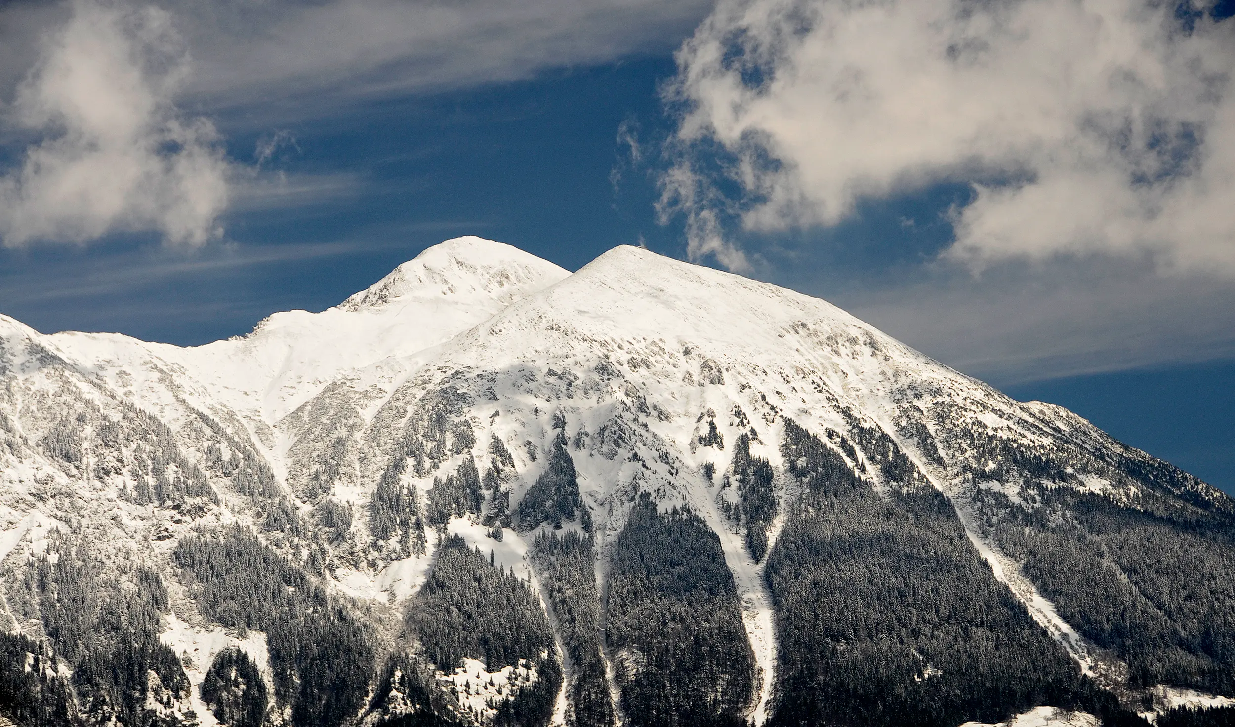 Snow-covered peaks under a bright sky, showcasing the winter beauty of the Slovenian Alps.