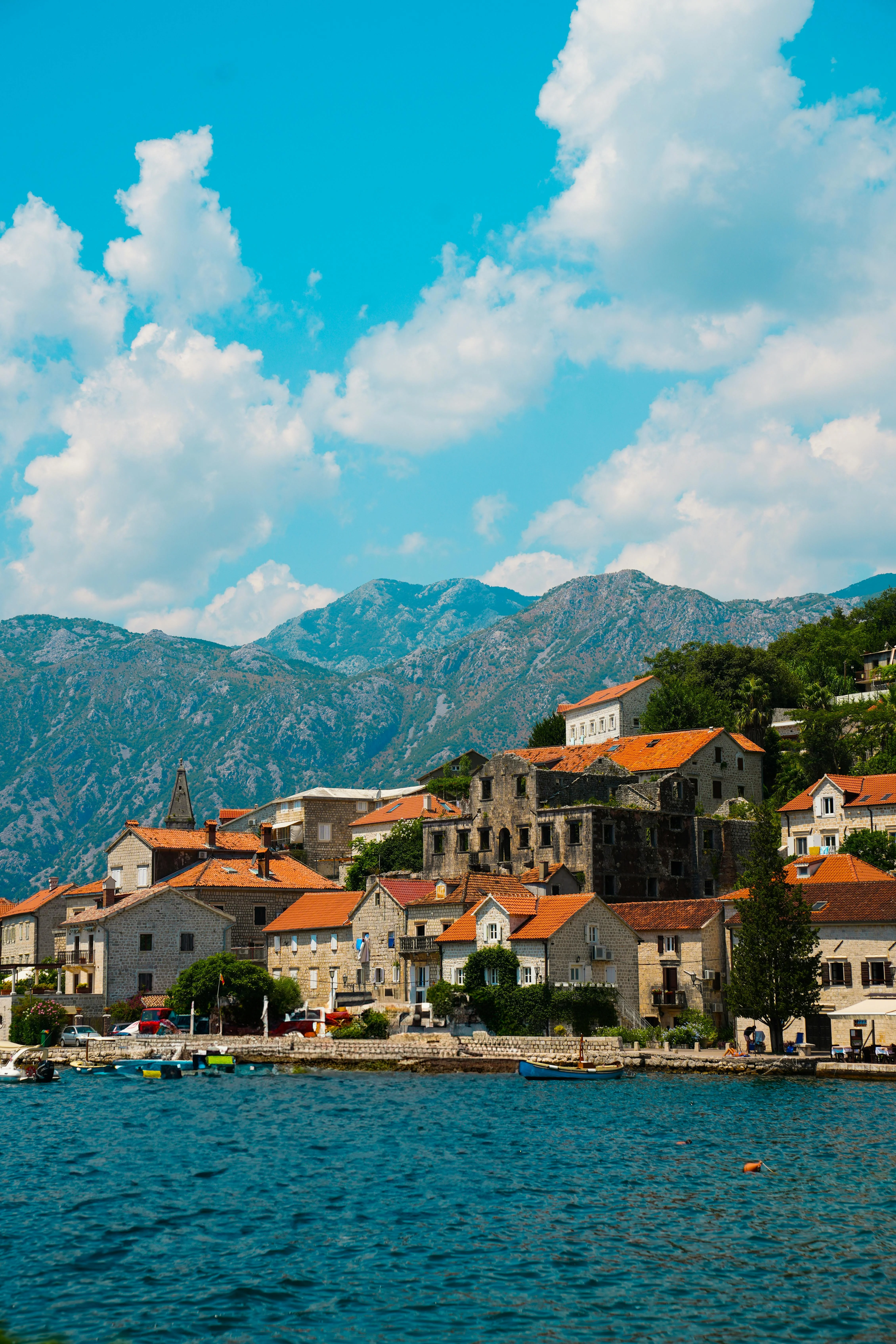 Perast, Montenegro - Scenic waterfront town with stone houses, red rooftops, and mountain views along the Bay of Kotor.