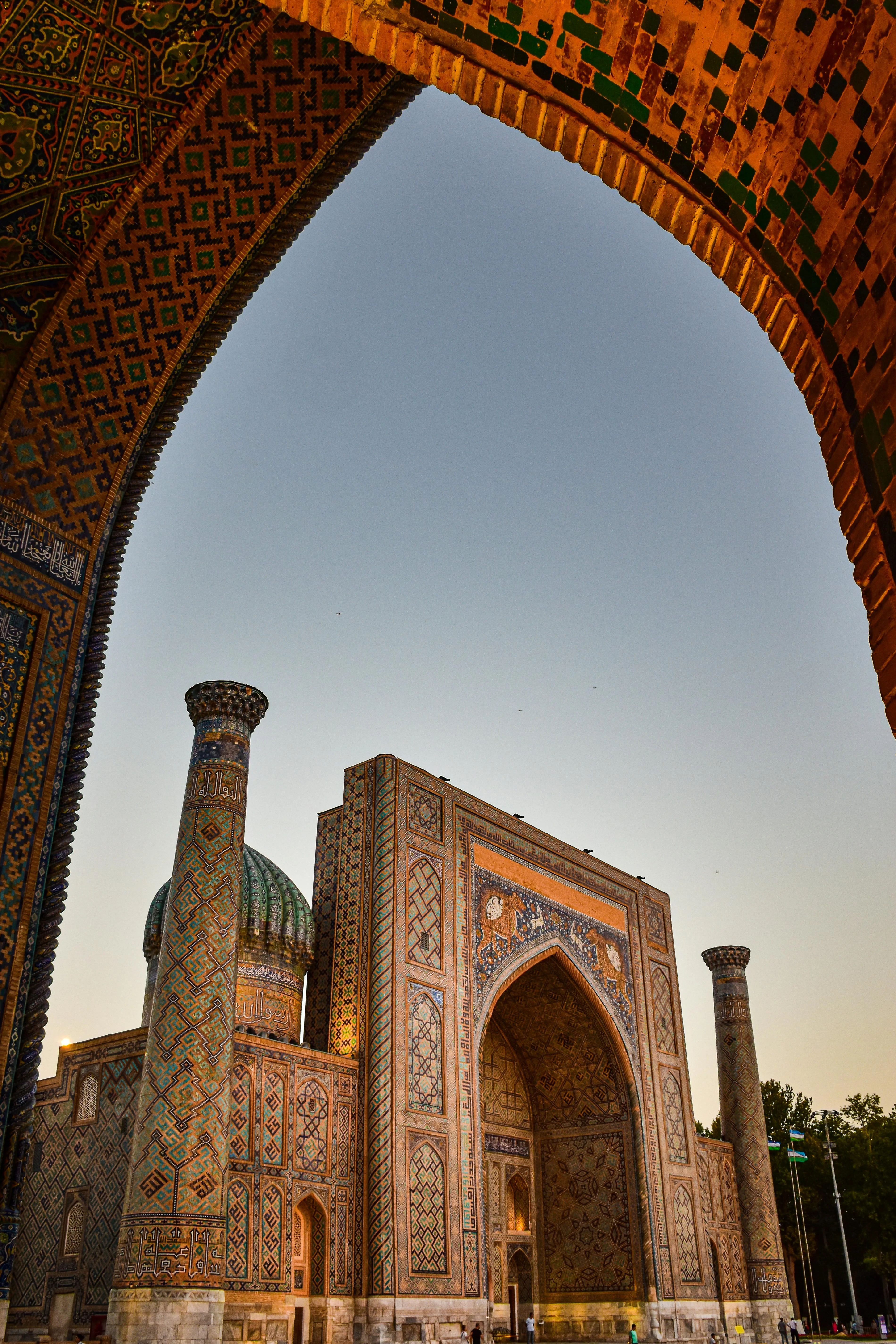 A stunning archway framing the intricate tilework of Registan Square, a jewel of Samarkand’s history.
