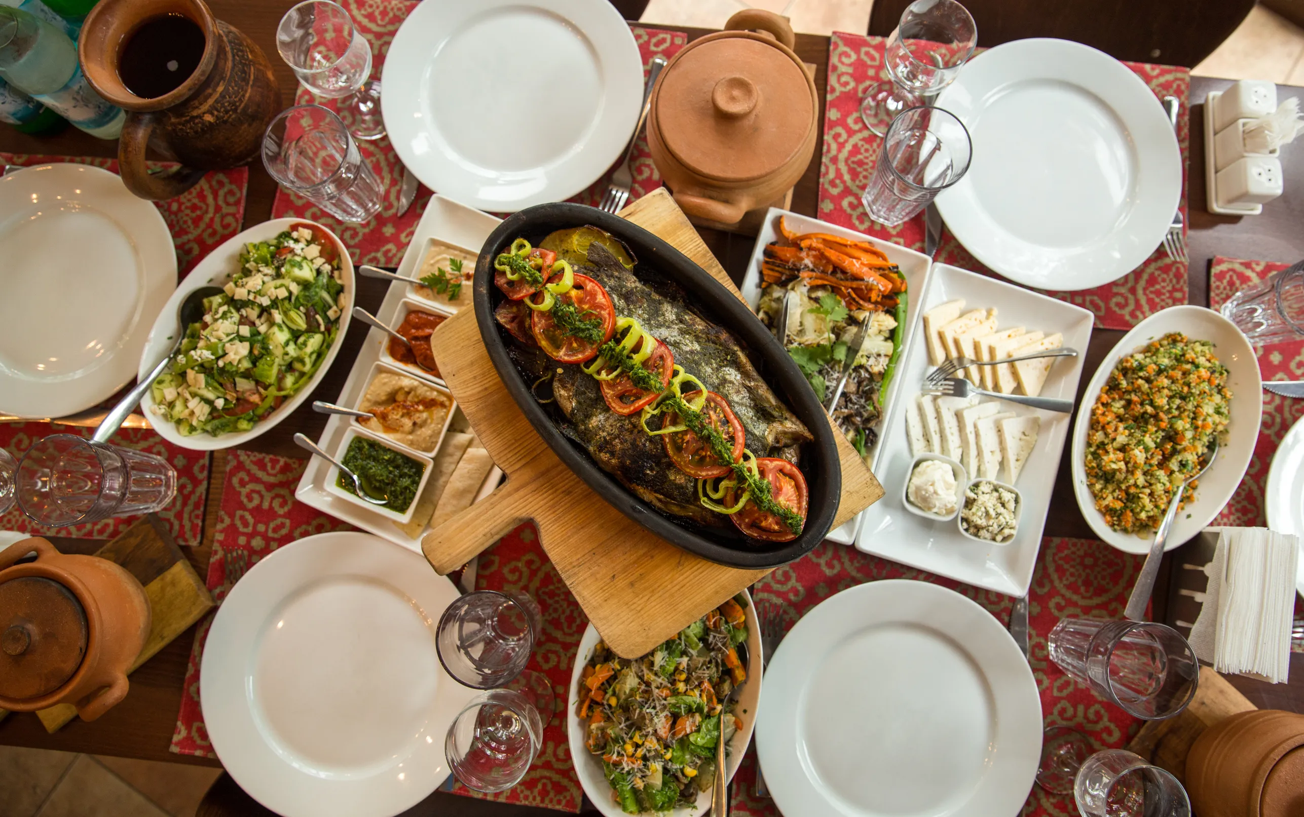 Traditional Armenian fish barbecue with grilled fish, fresh salads, and dips, served on a rustic table.