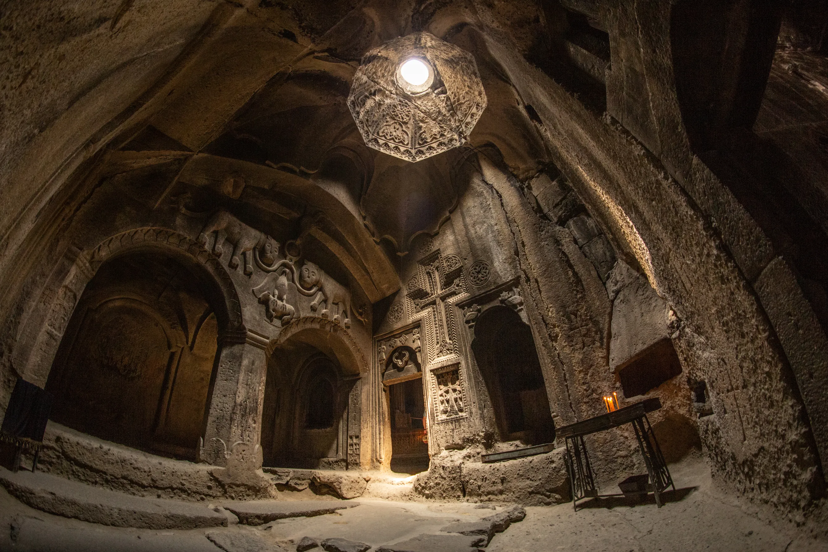 Interior of Geghard Monastery, Armenia, a UNESCO site carved into rock with intricate medieval stonework.