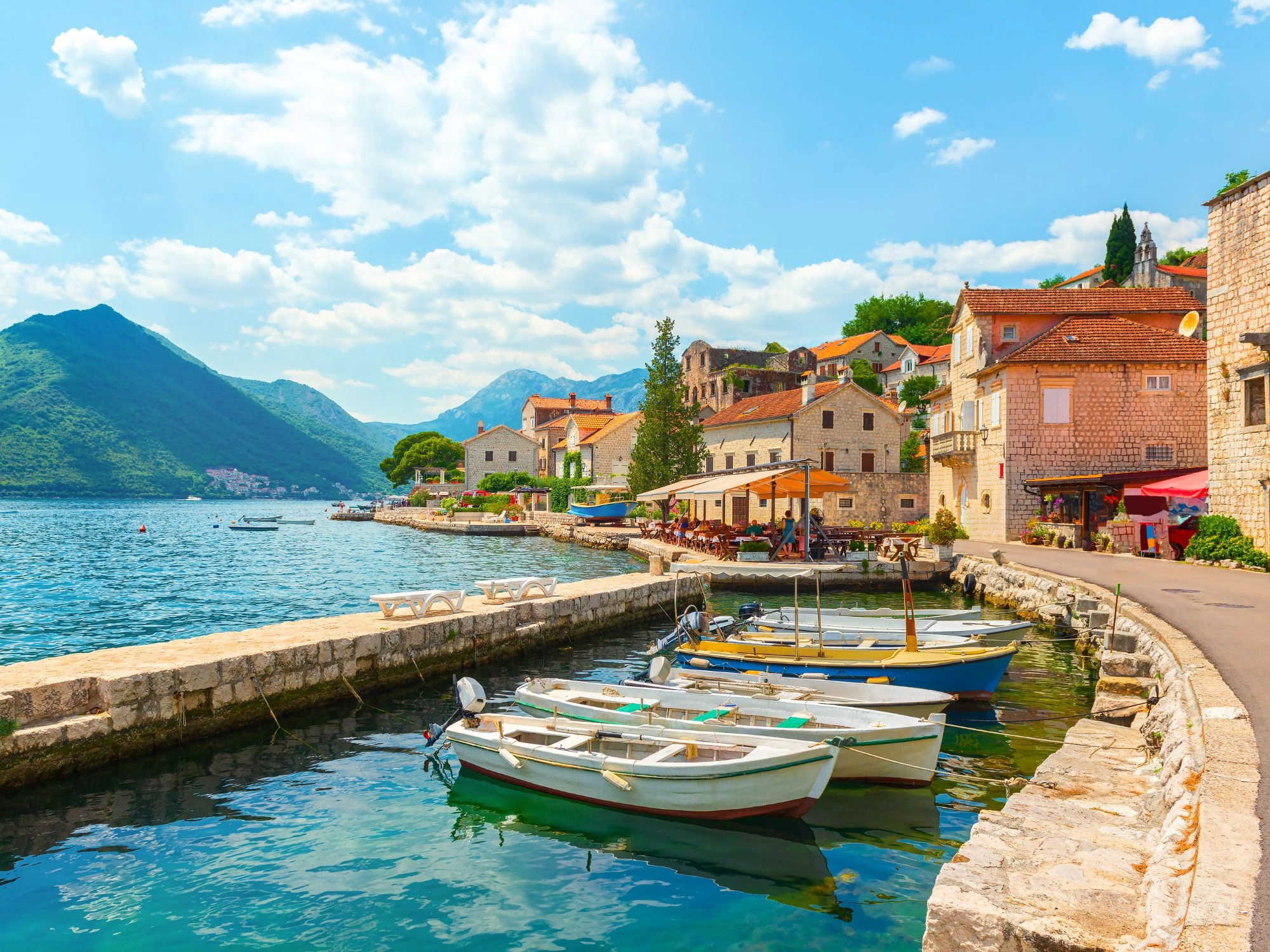 Montenegro Perast – boats docked in calm bay alongside charming stone buildings and cafes.