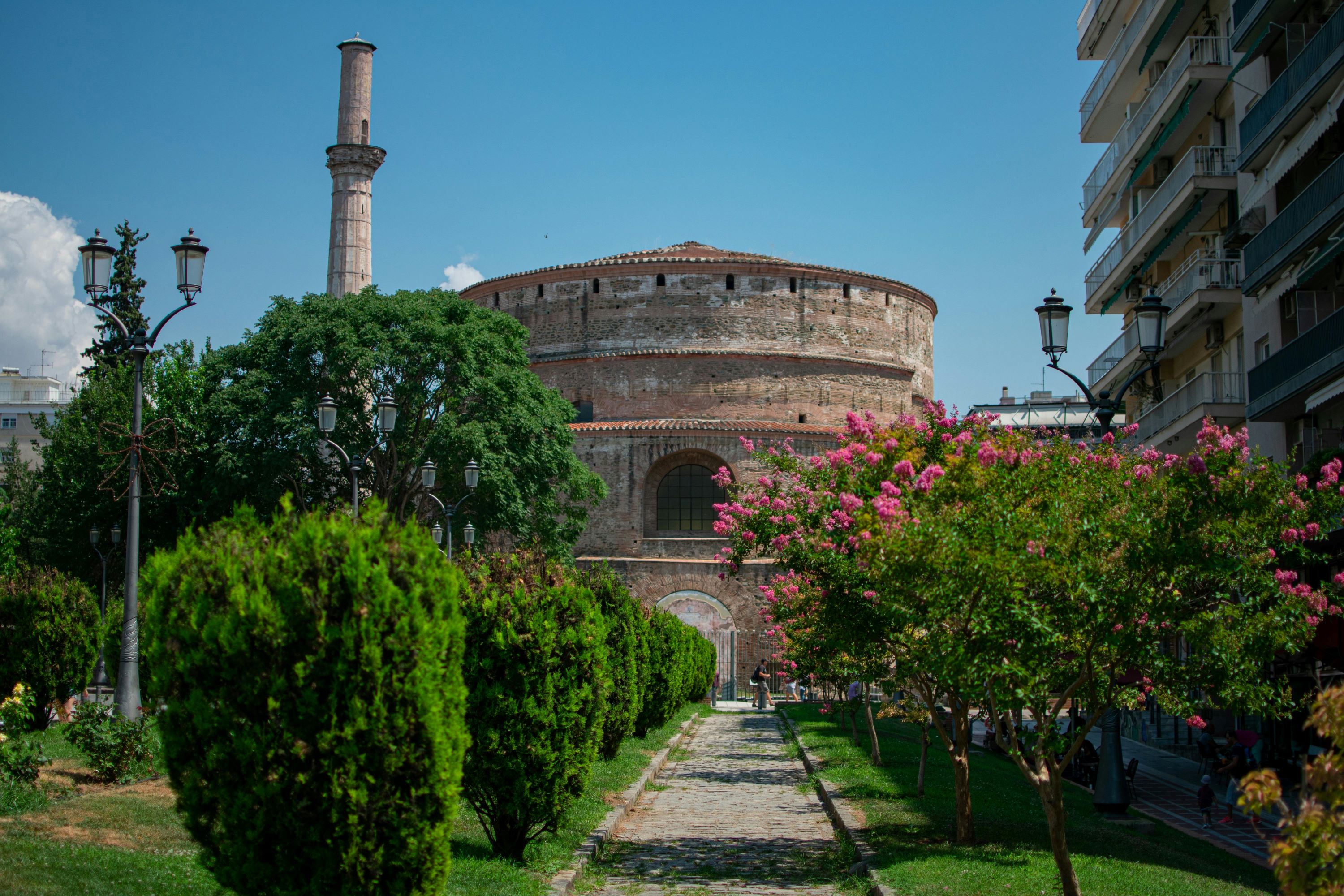 Thessaloniki people – city garden view of Rotunda and minaret, surrounded by trees and urban life.