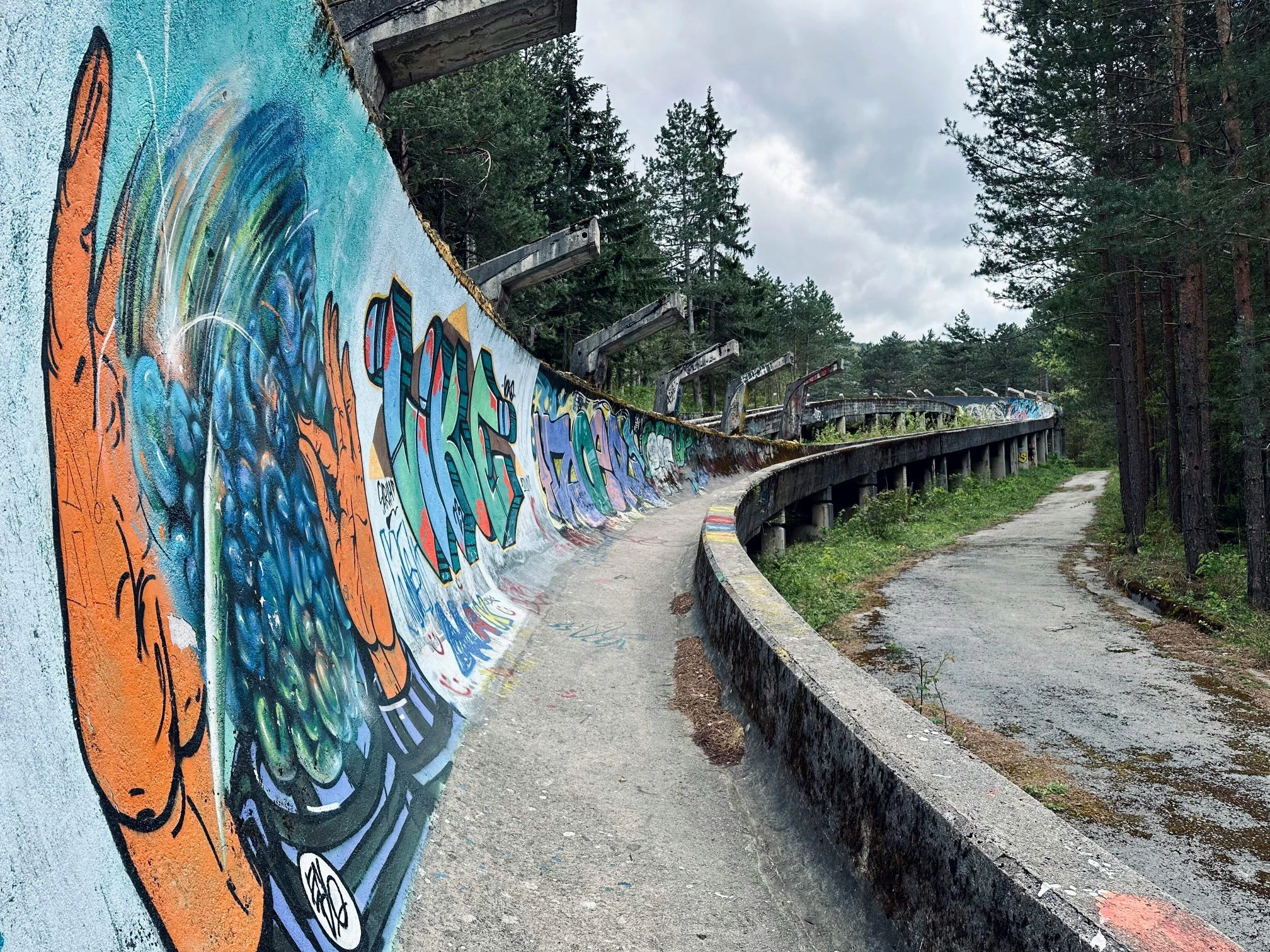 Sarajevo Bobsleigh Track, Bosnia – graffiti-covered Olympic track winding through pine forest.