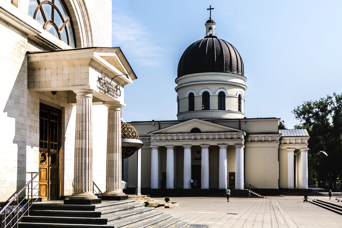 Chisinau Cathedral with neoclassical pillars and black domed roof under clear sky.