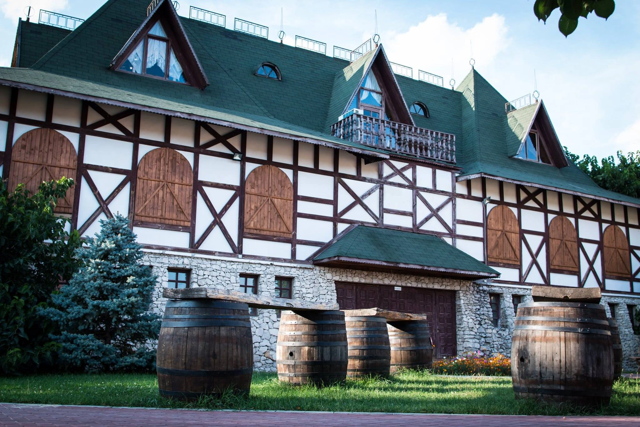 Exterior of Asconi winery in Moldova with rustic barrels and timber-framed building under green roof.