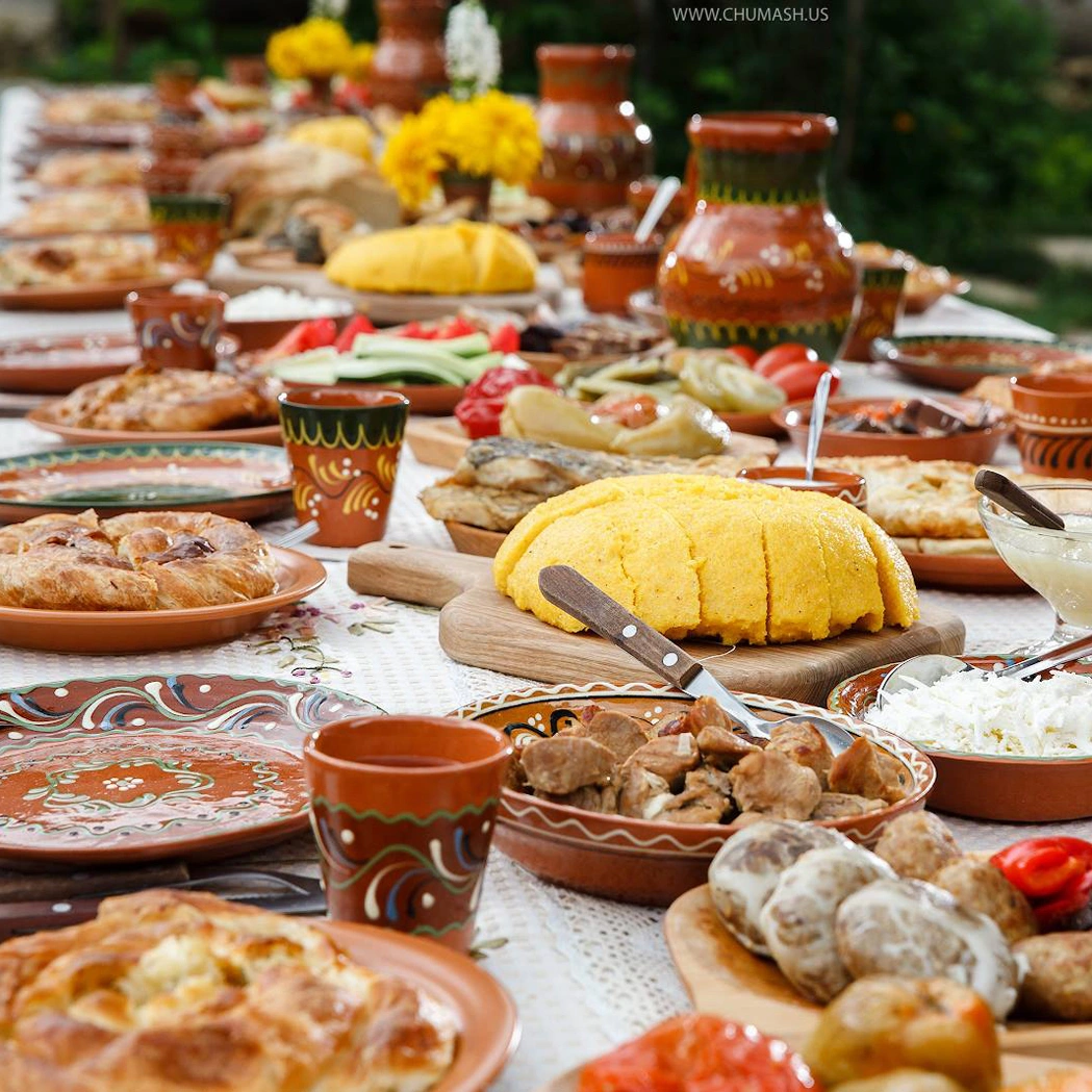 Moldovan traditional feast with mamaliga, meats, pies, pickled veggies, and rustic plates.