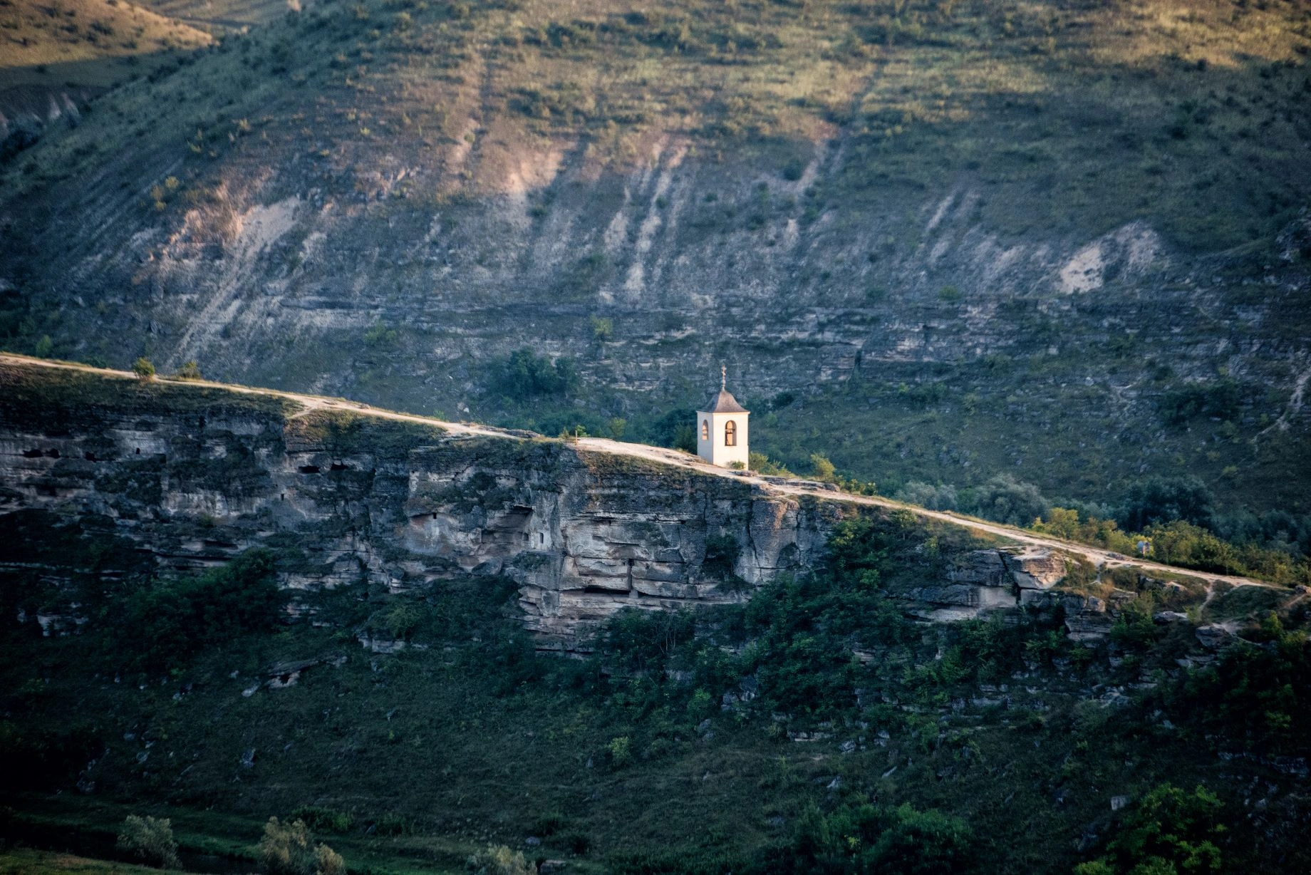 Small white church perched on a cliffside at Orheiul Vechi historical site in Moldova